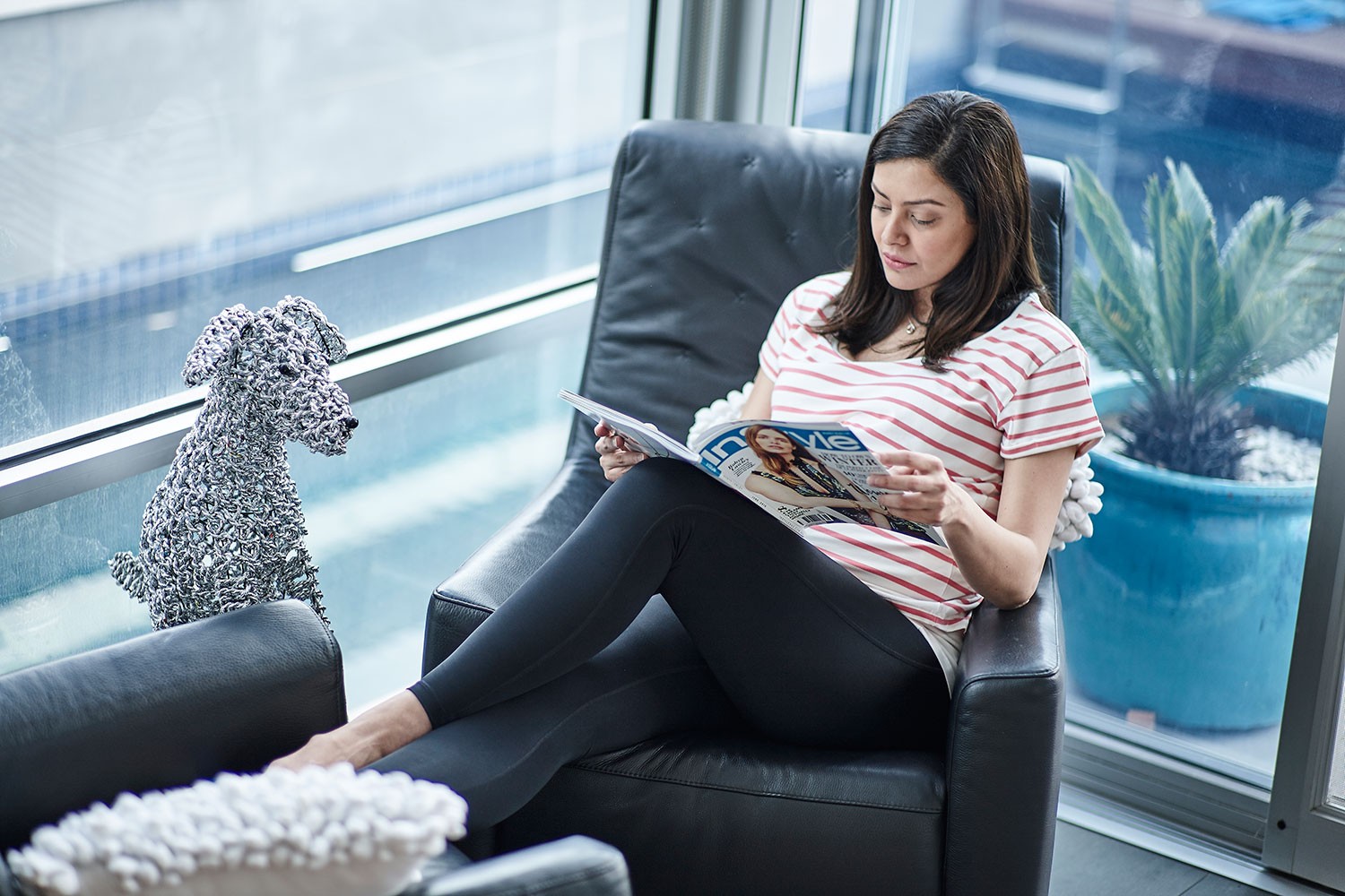 Pregnant woman wearing maternity leggings while sitting on a couch reading a book, finding comfort and support for bump related issues during pregnancy