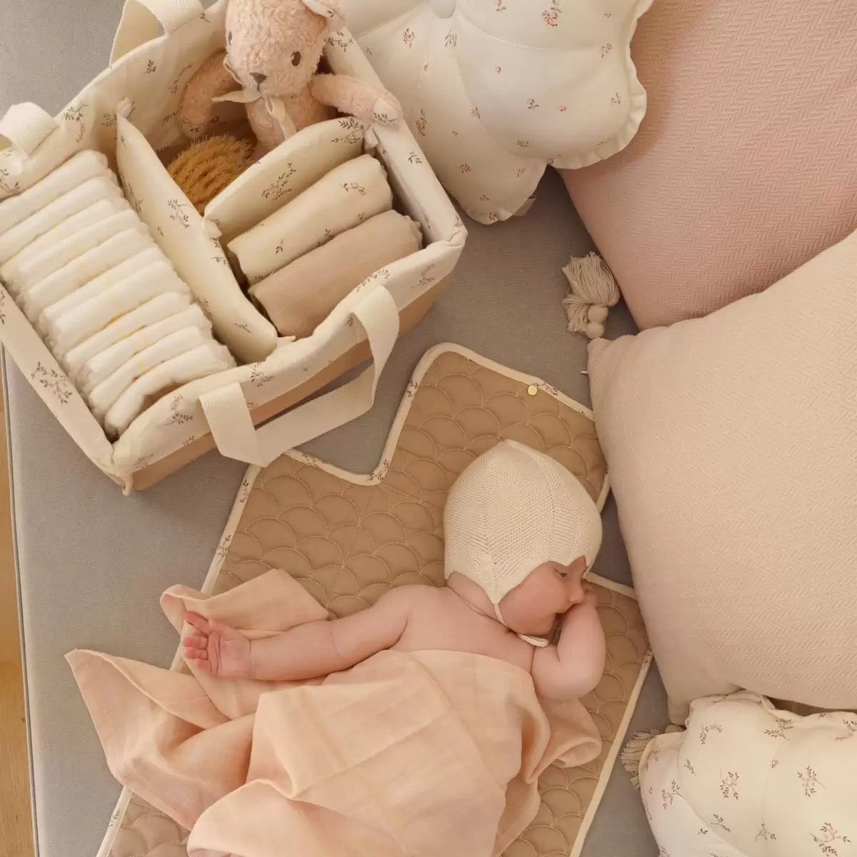 Cam Cam Copenhagen nappy caddy in Ashley print filled with baby essentials beside a newborn during nappy change time