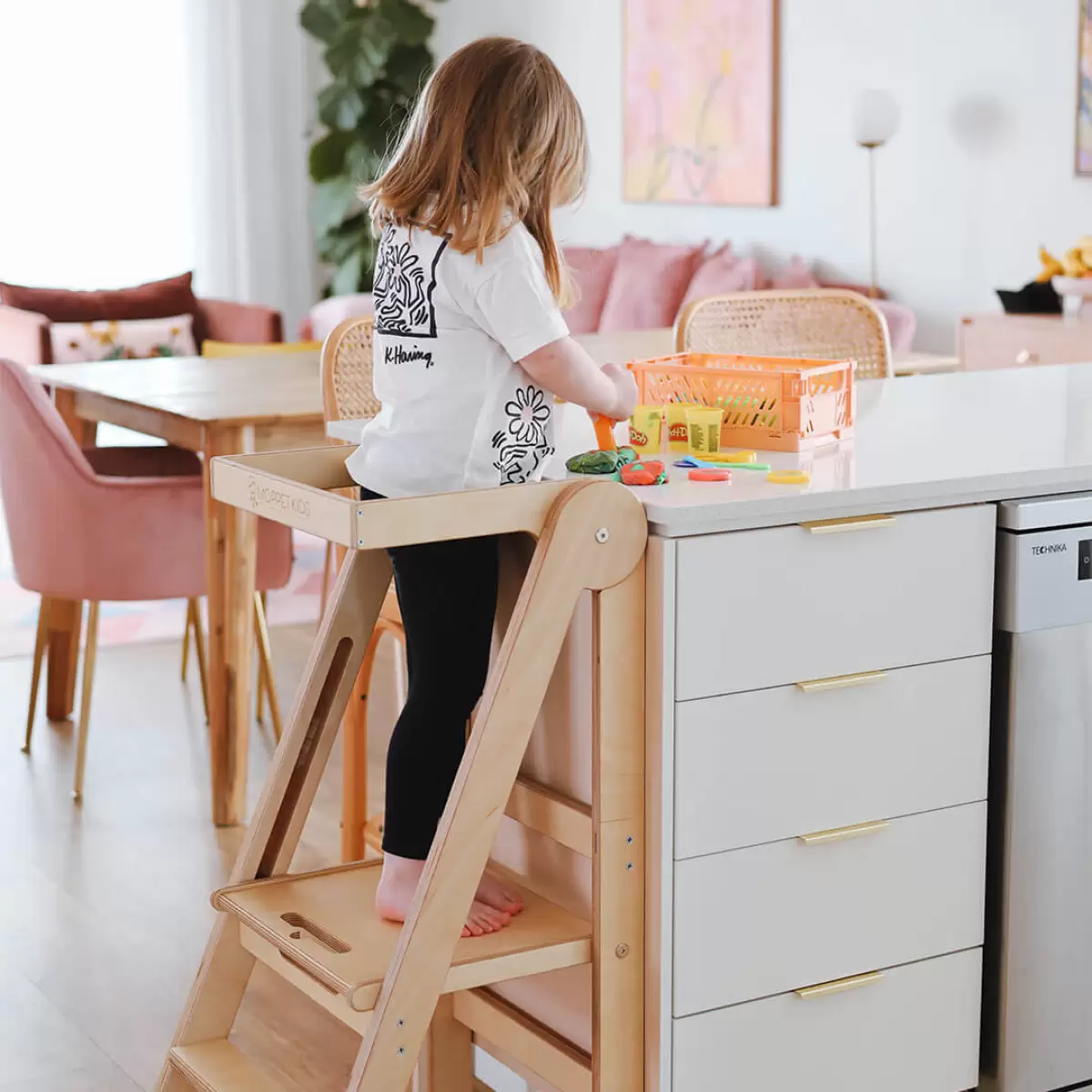 Toddler playing with play-doh on the kitchen counter while standing safely on a folding learning tower