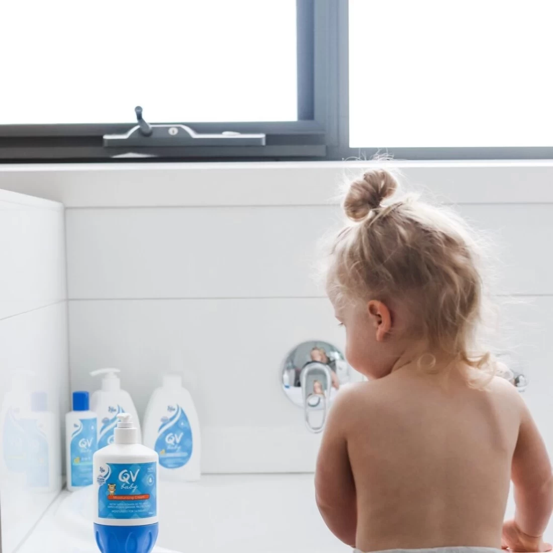 Baby girl enjoying bath time with QV Baby Skincare products