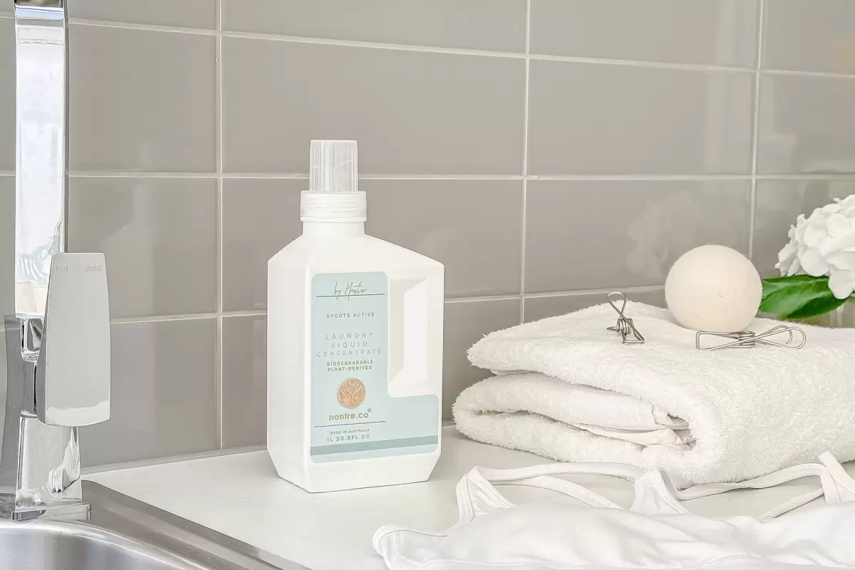 Best cleaning products in a modern laundry – Nontre Laundry Liquid Concentrate beside clean white towel and activewear top.