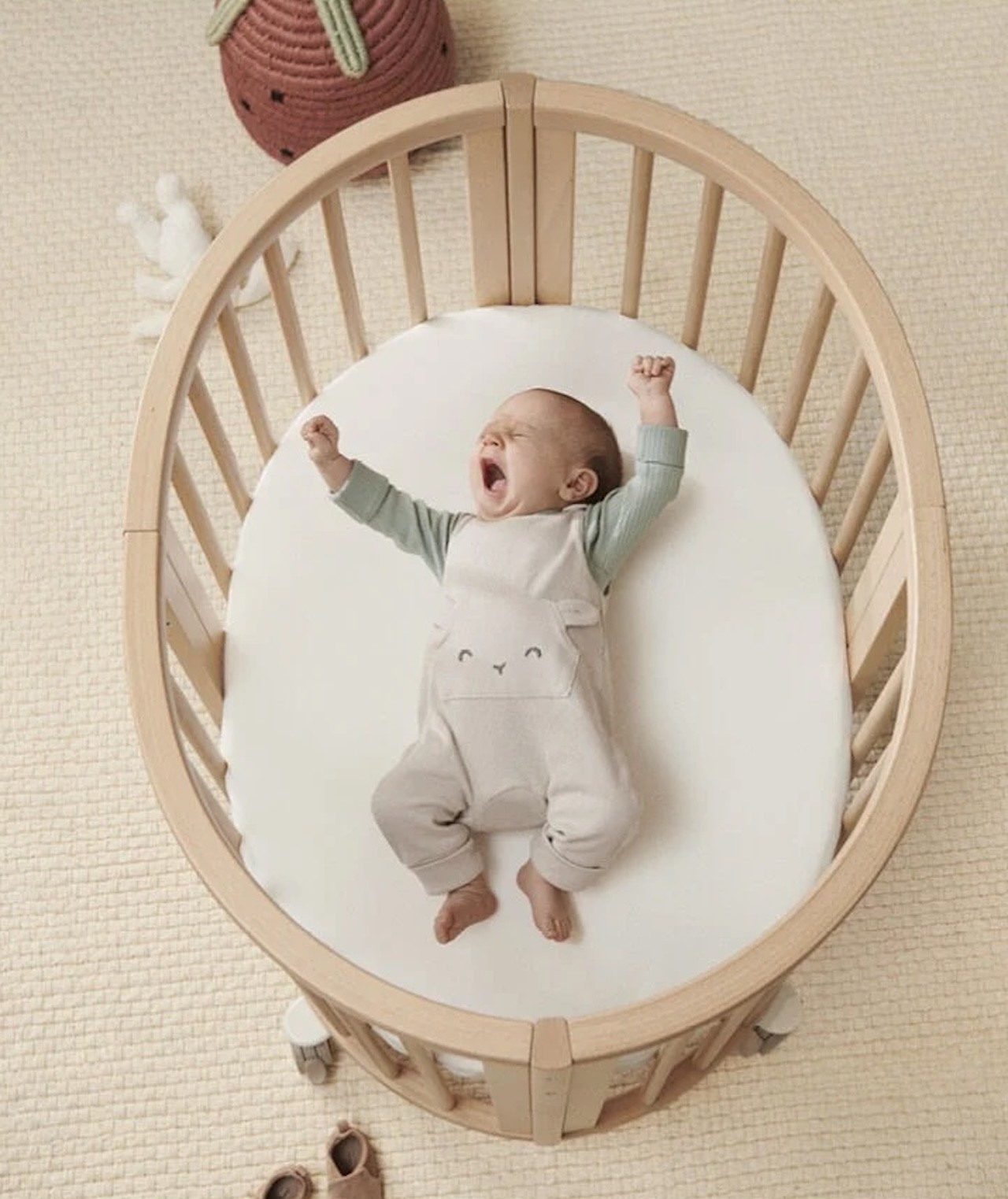 The Stokke Sleepi baby bassinet with a baby yawning in it