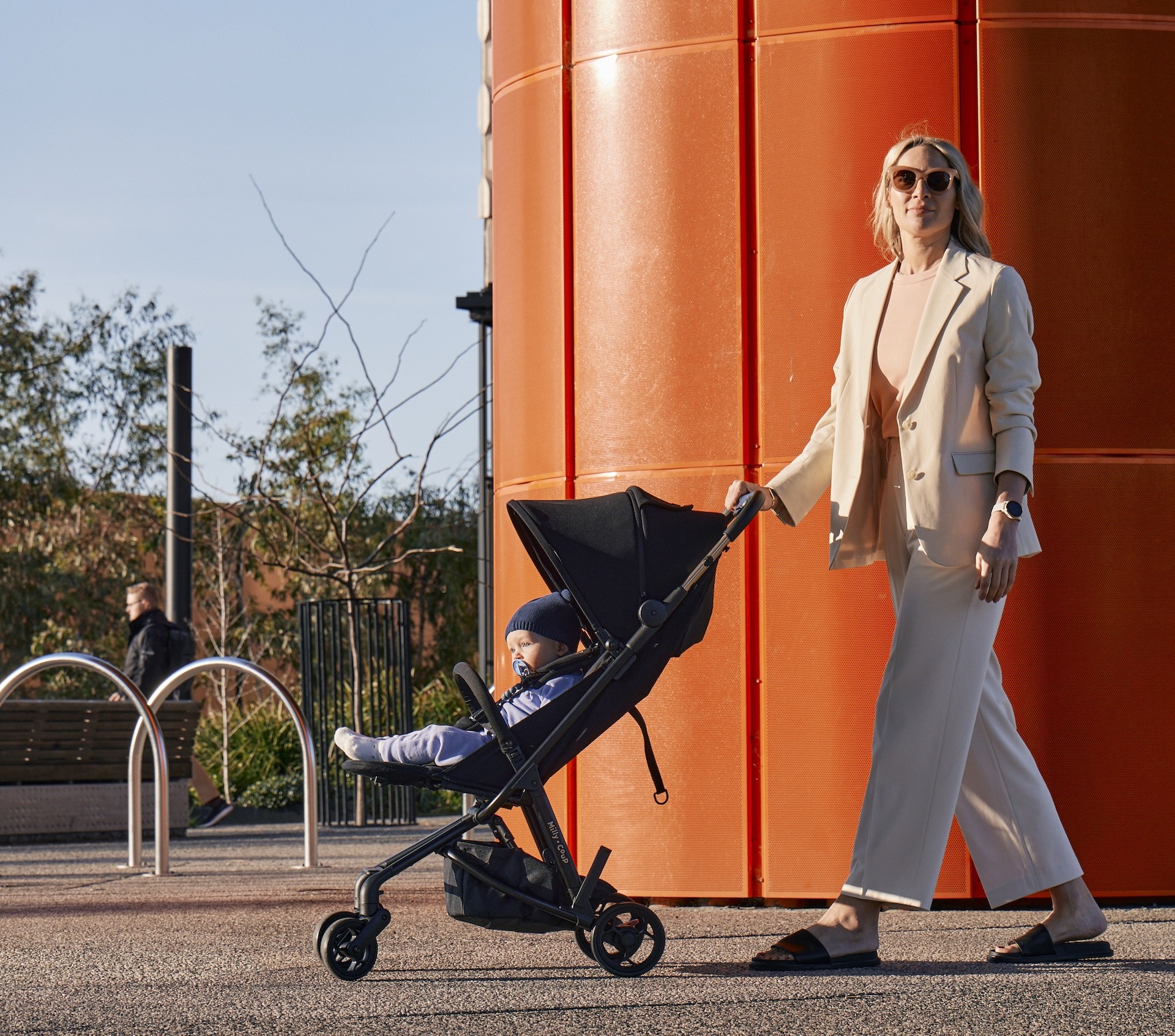 A mum walking her baby in a Milly + Coup PIXI travel pram