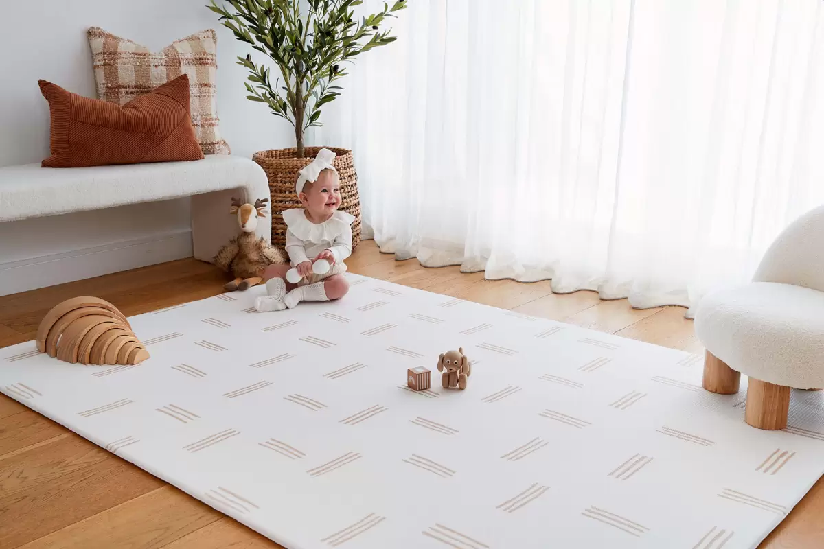 Comfortable padded childrens play mat in a modern nursery with a toddler playing happily on the floor.