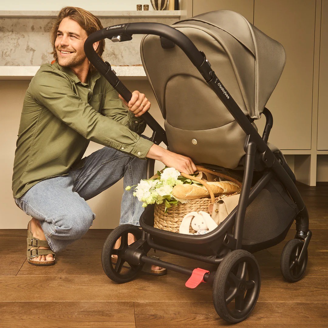 A dad showing the generous storage space below the Babybee Alto pram