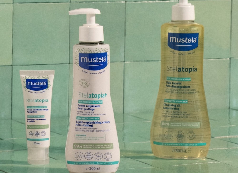 Mustela Stelatopia baby eczema range shown in a bathroom with green tiles