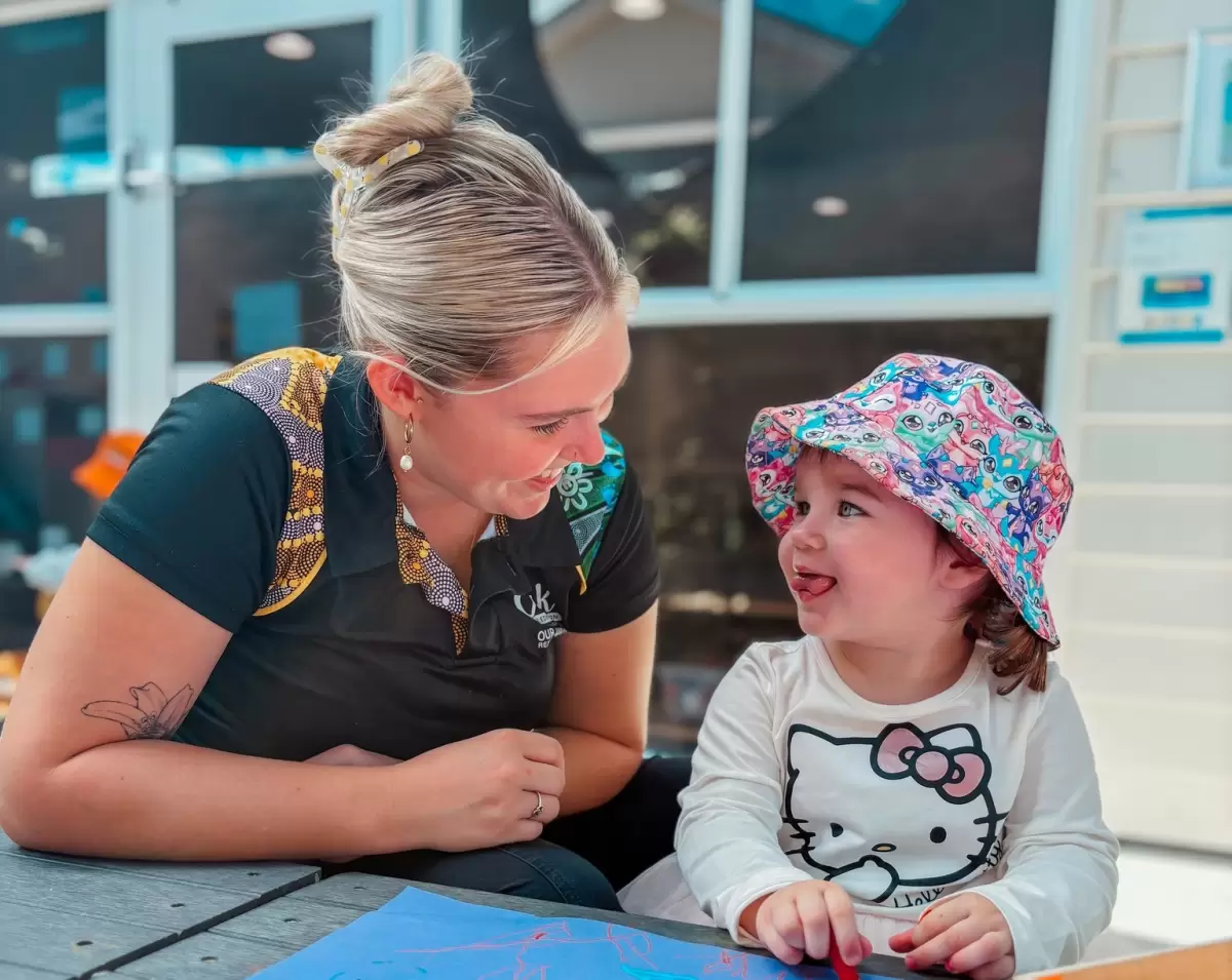 Educator supporting a young child with artwork at Australian best childcare centre