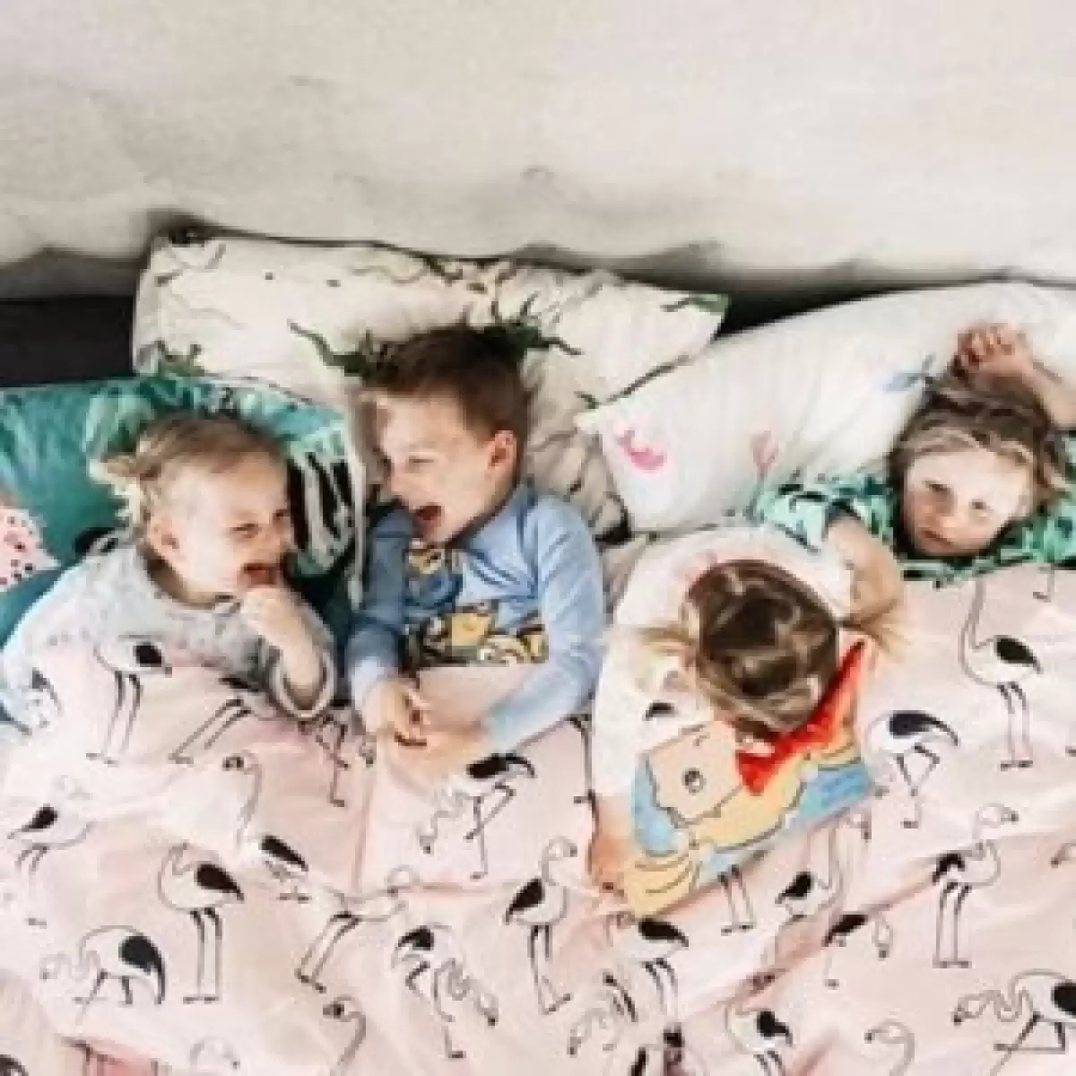 Kids laughing together in Sack Me baby sleeping bags on the bed, perfect for travel and sleepovers.