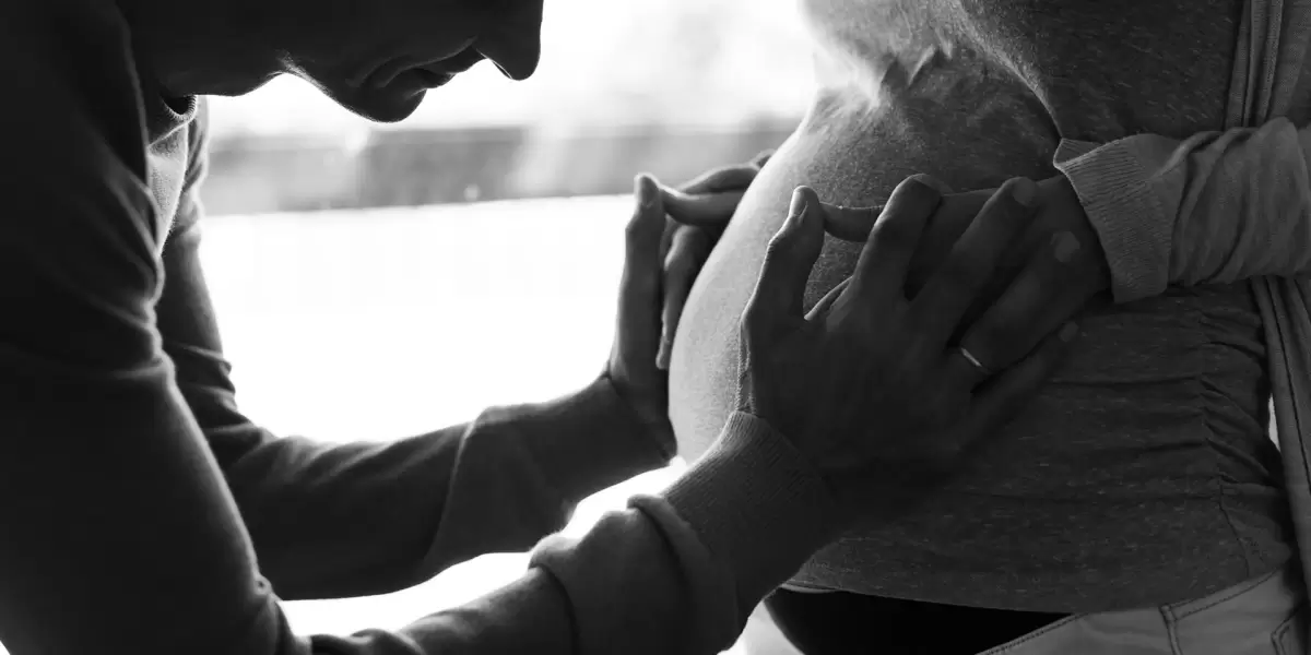 Birth partner offering calm reassurance as pregnant woman holds her belly – a touching moment that captures how a birth partner can help during labour.