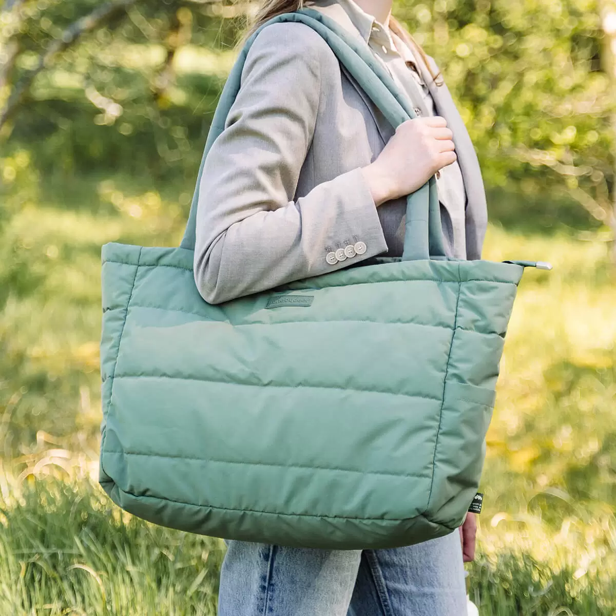 Hands-free park stroll with best diaper bag Australia – Done by Deer Quilted Tote in green slung over mum’s shoulder.