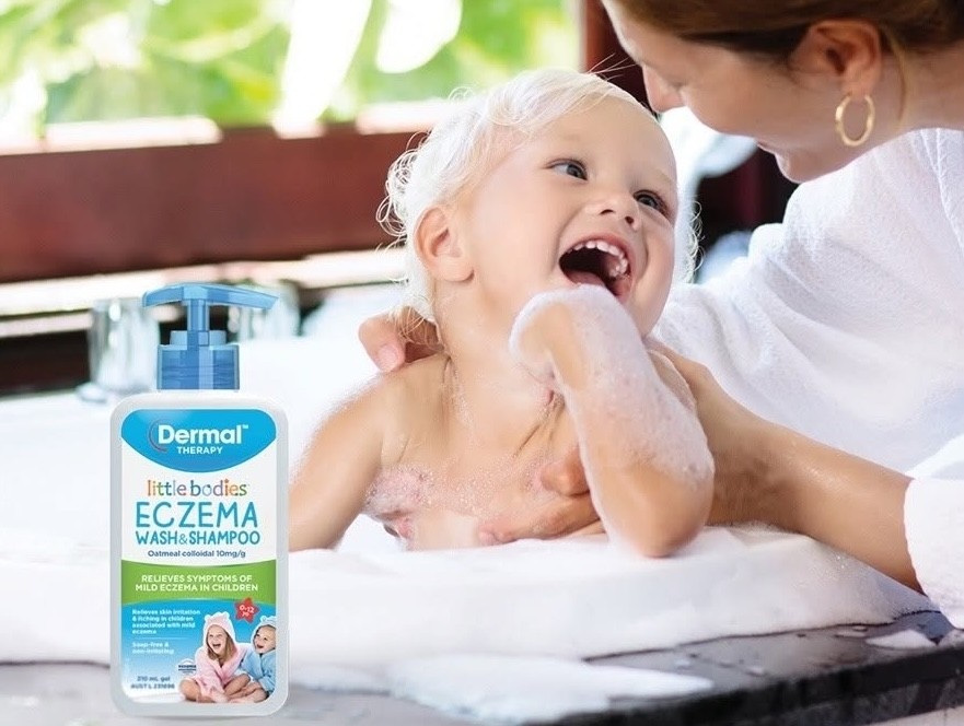 A baby laughing in the bath with dermal therapy eczema wash nearby