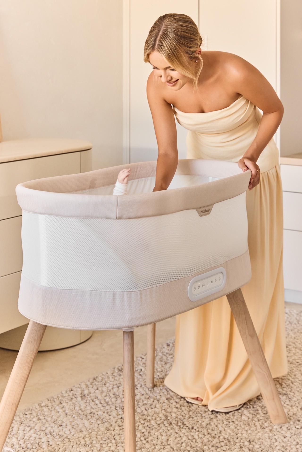 The Redsbaby KIPP Smart baby bassinet shown with a mum settling her baby in it