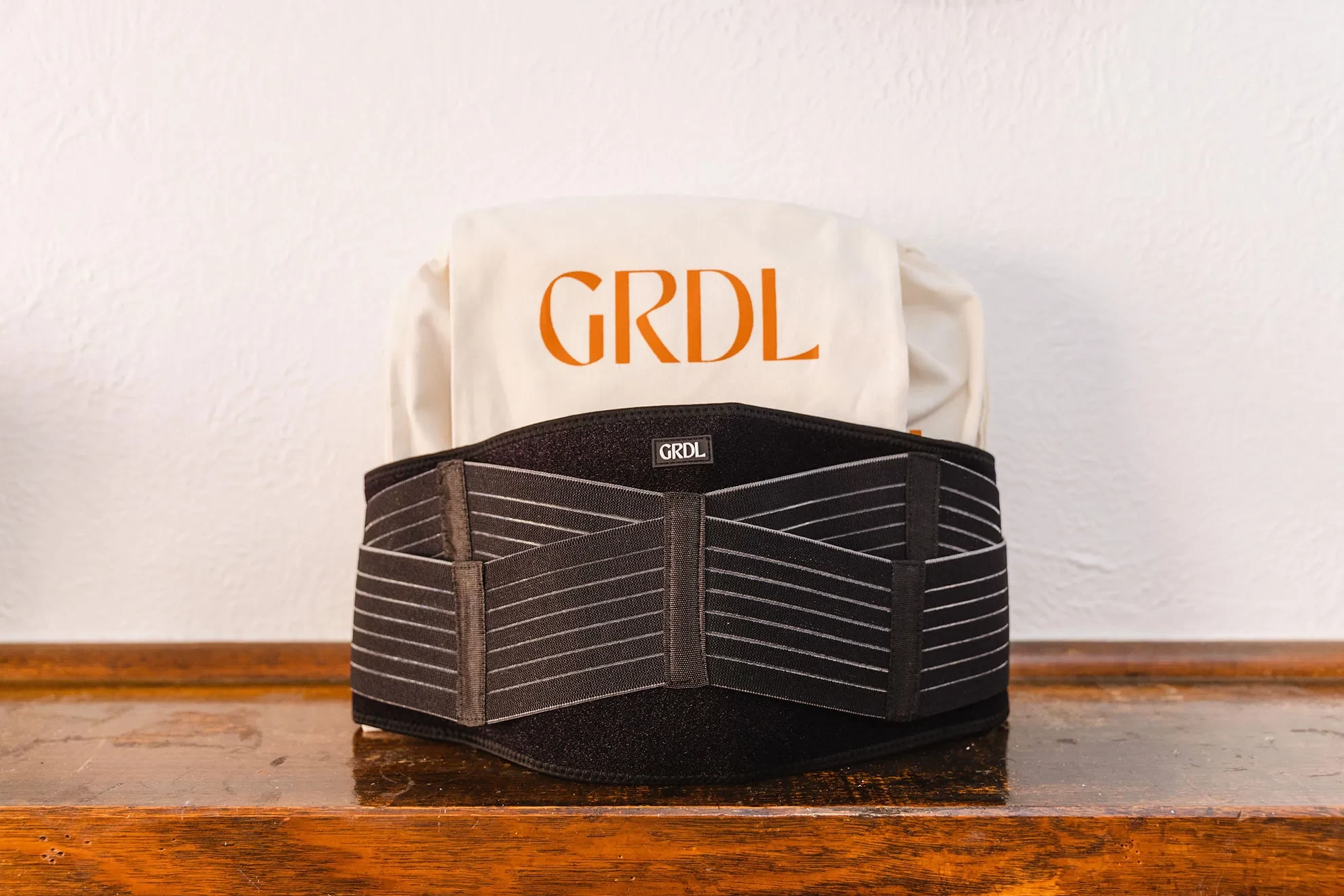Close-up of black GRDL Pregnancy Belt on wooden surface, the best belly bands pregnancy for mums-to-be.