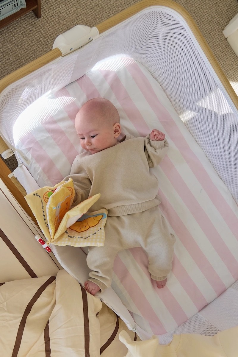 A baby lying on pink striped bassinet sheets