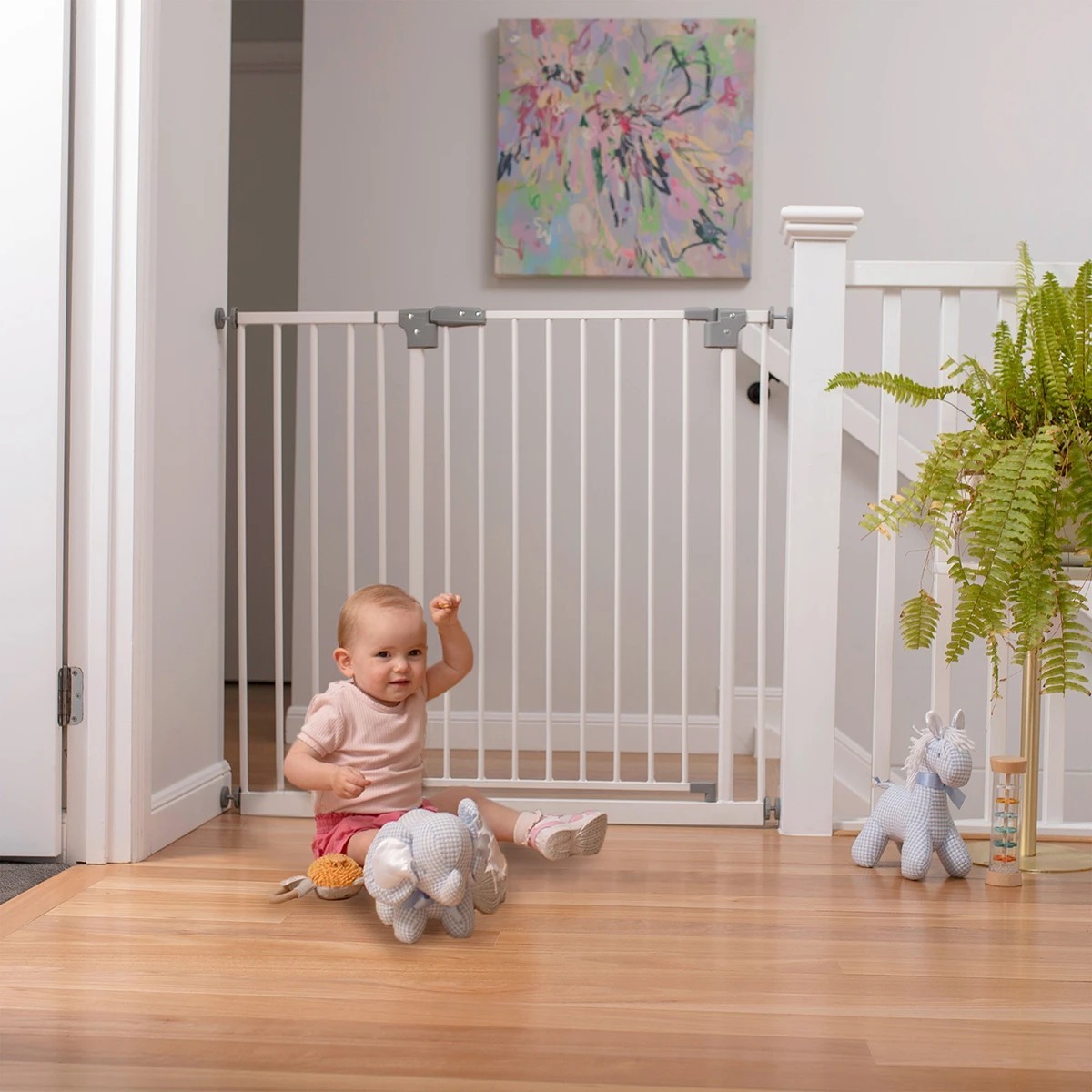 A baby sitting in front of the kmart baby safety gates