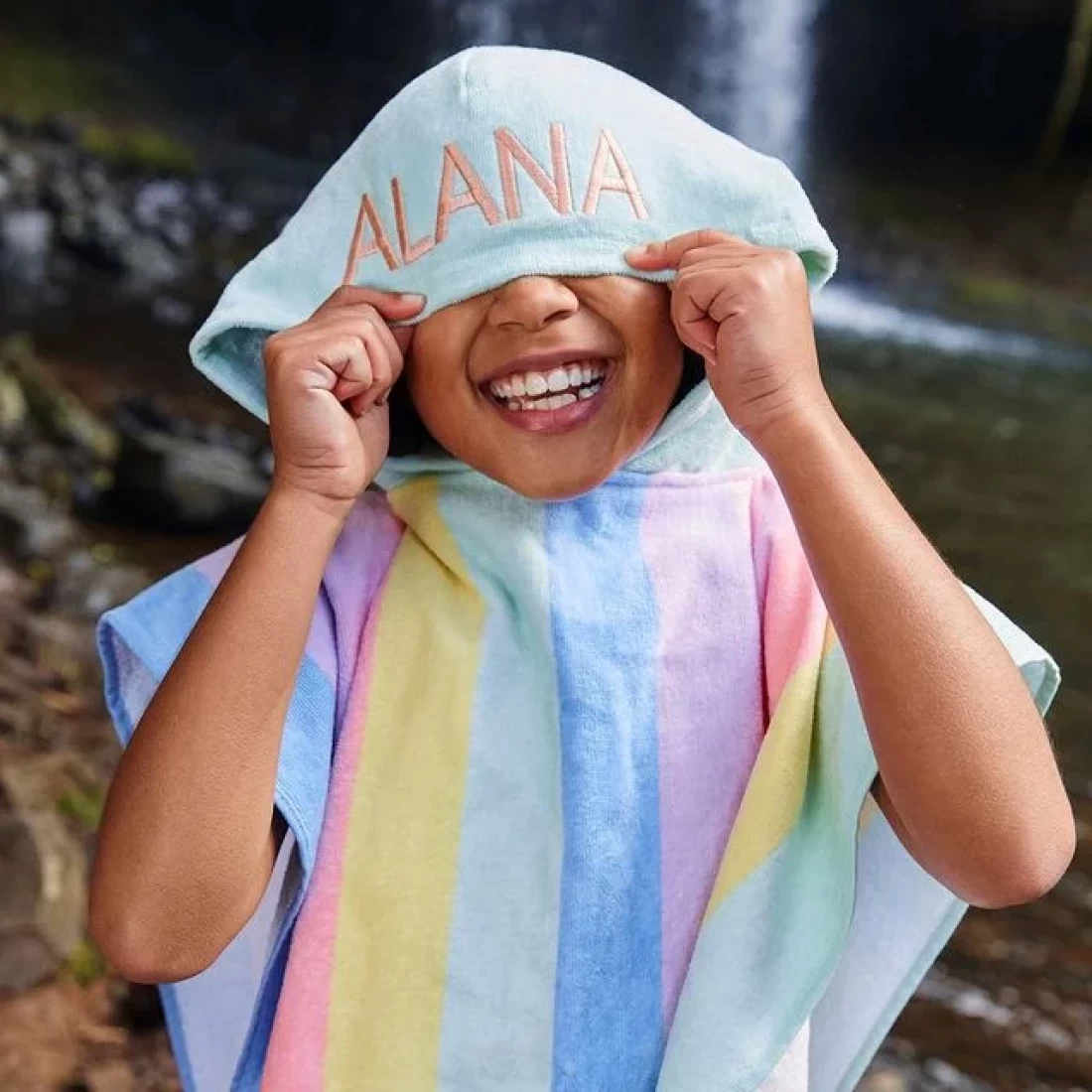 Kid covering her face with the hood of the best hooded beach towel, perfect for sun protection