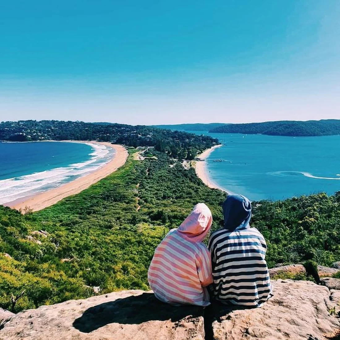 Two kids on a mountaintop overlooking the beach, wearing the best hooded beach towel.