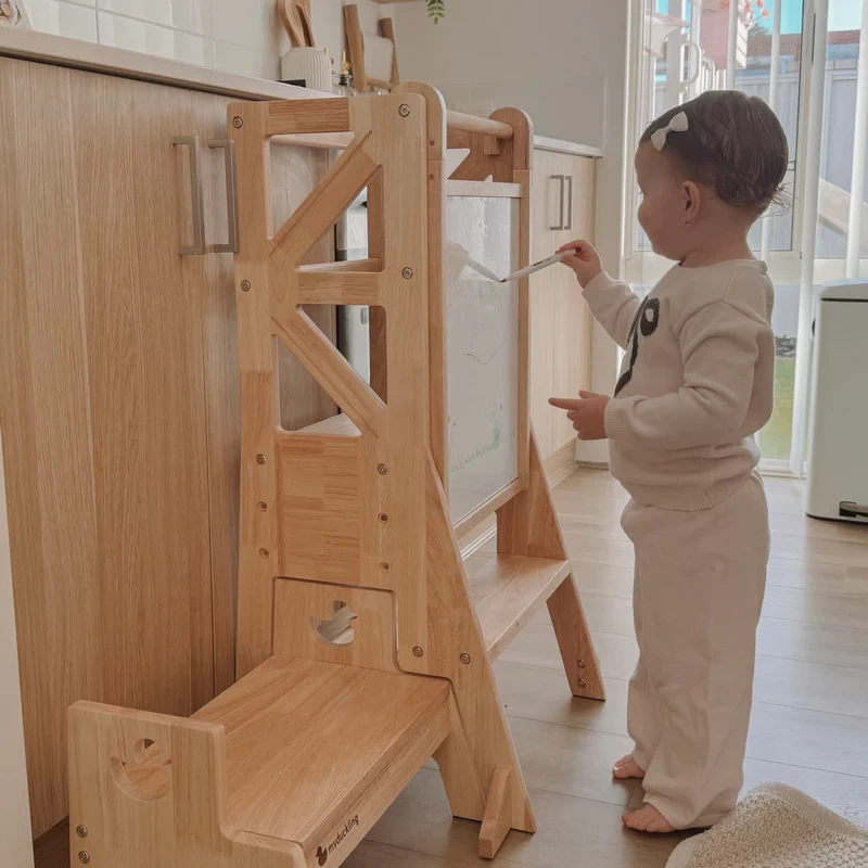 A toddler drawing on the whiteboard portion of their learning tower
