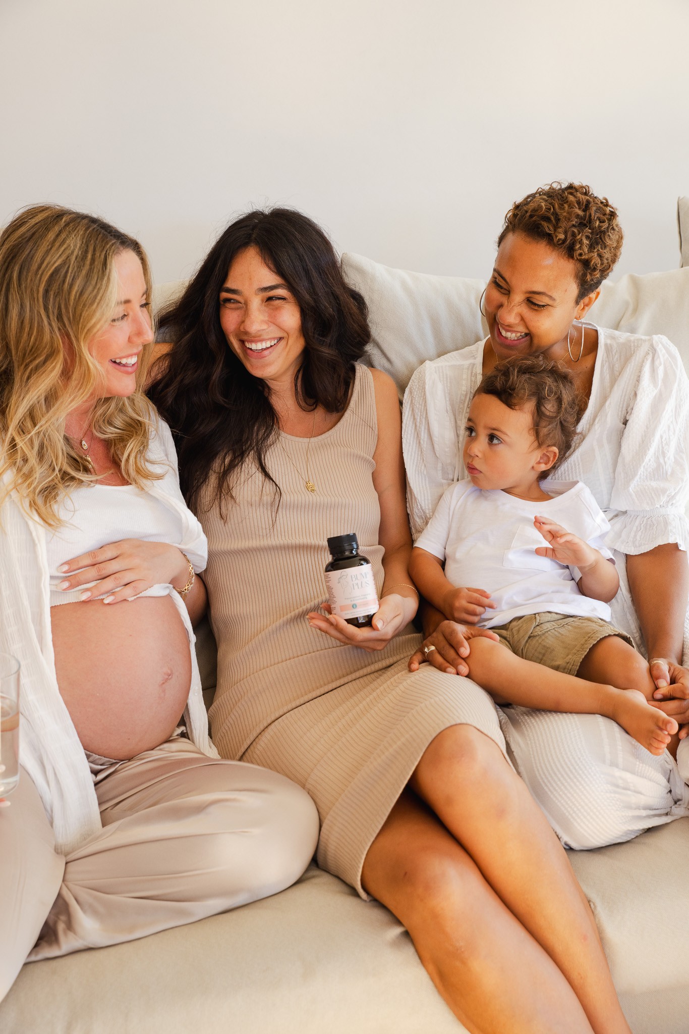 Two pregnant mums and one mum holding a baby with a visible bump, all holding prenatal vitamins