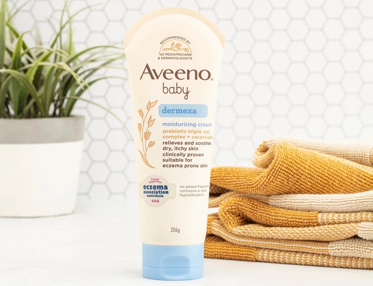 Aveeno baby lotion shown in a bathroom with towels nearby