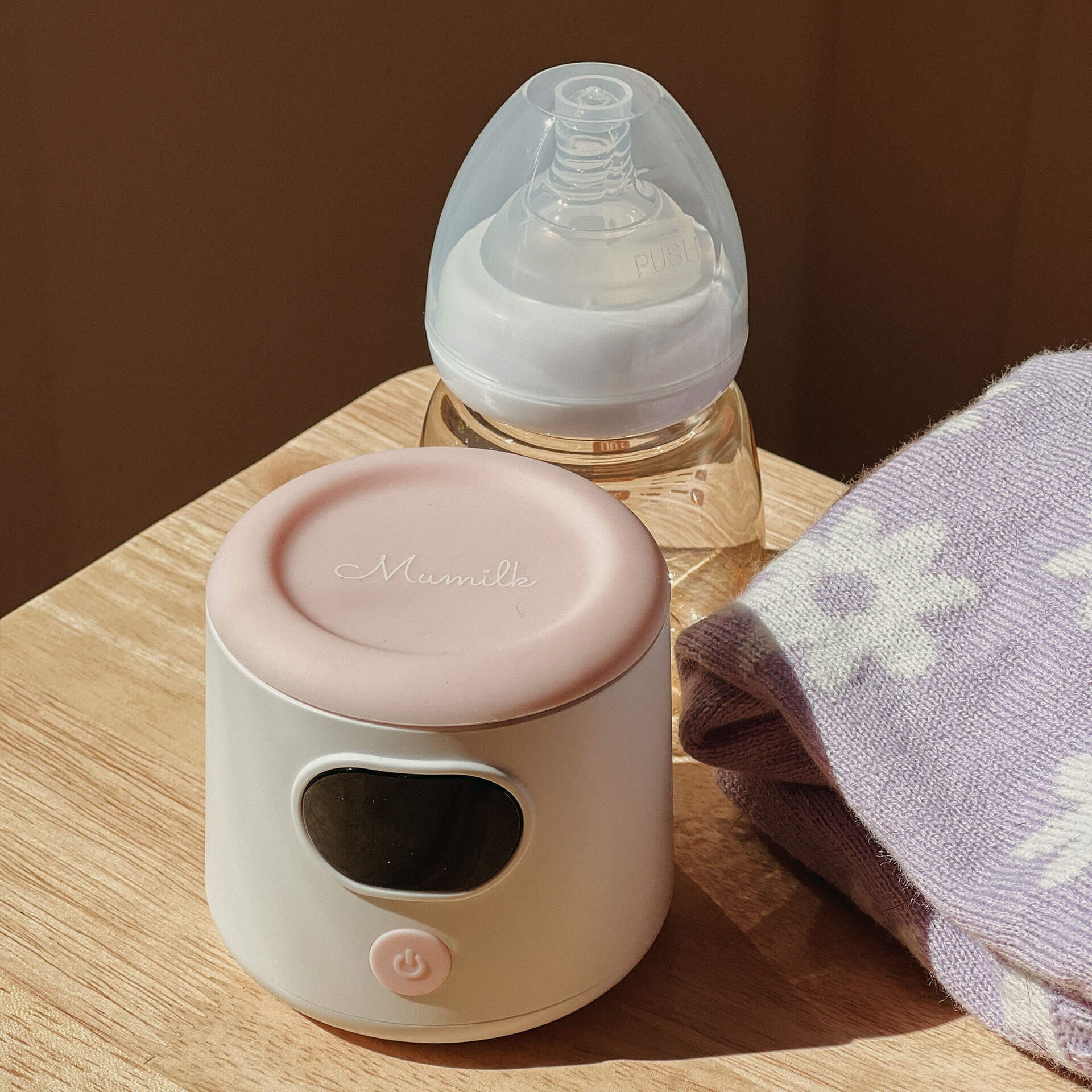 Compact portable bottle warmer next to baby essentials on a wooden table – ideal for parents searching the best bottle warmer Australia.