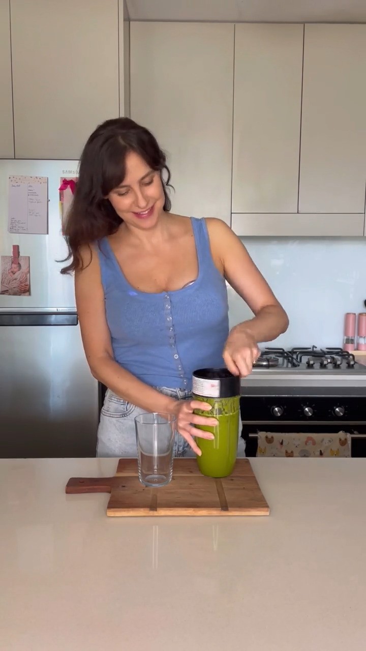 Mother in the kitchen using a smoothie maker while wearing the Night Owl Mumma Owl wearable Breast pump.