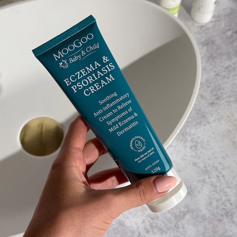 A woman holding the moogoo baby eczema product over a sink