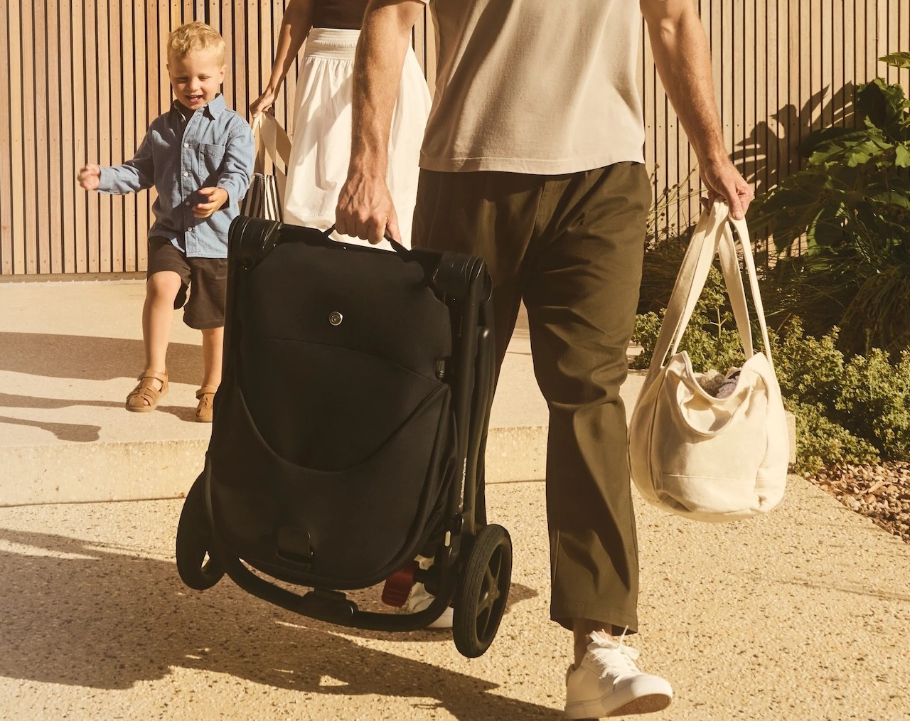 A dad carrying the Babybee Alto pram folded down, to show how compact it is