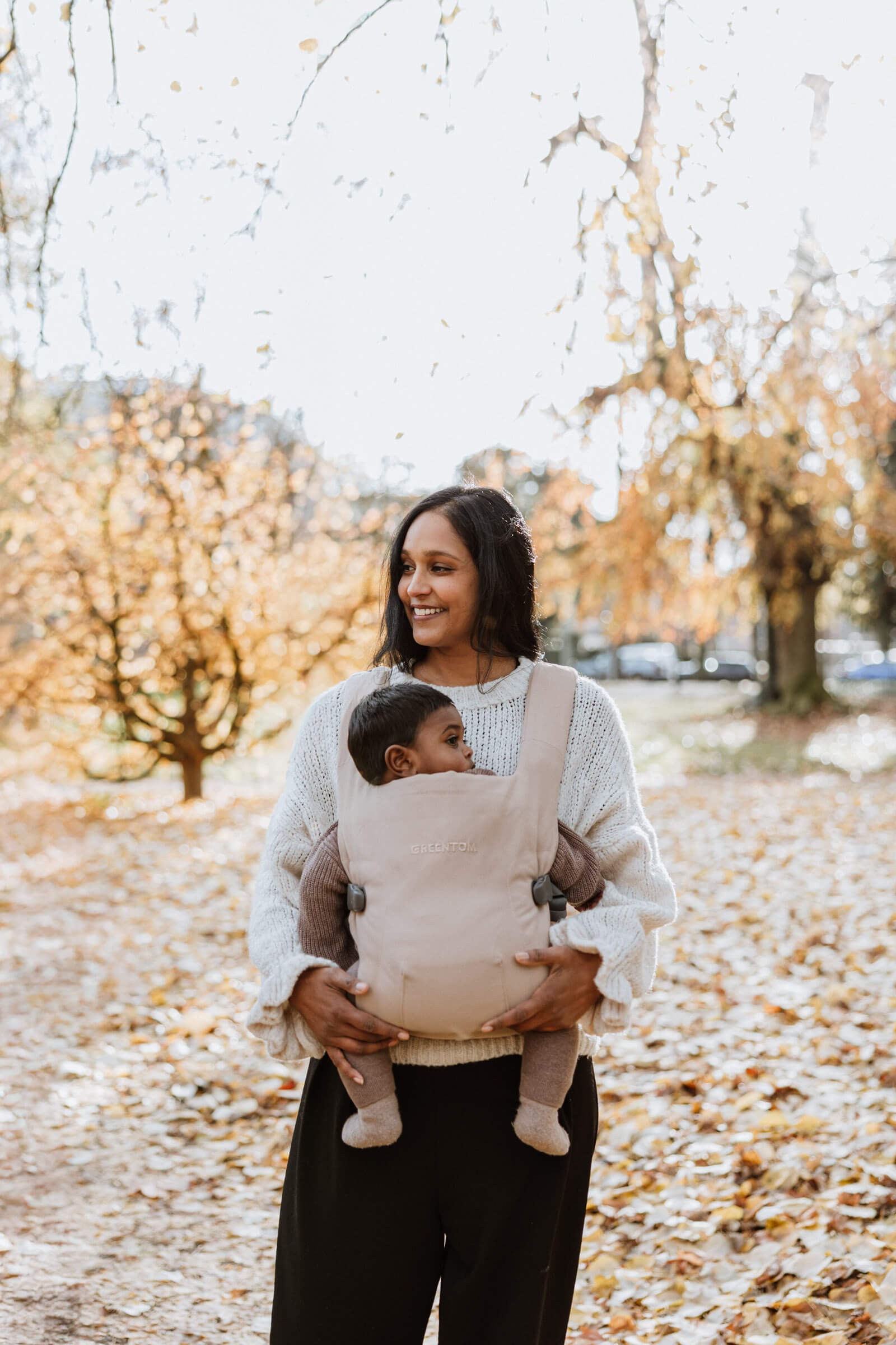 A woman carrying a baby in autumn season
