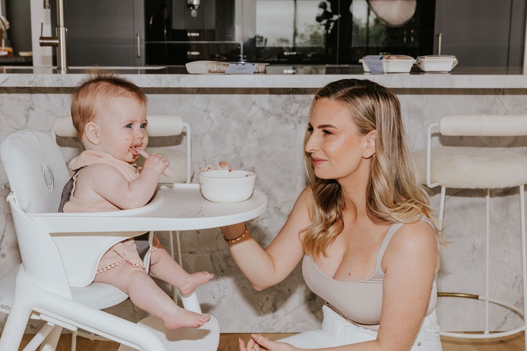 Baby eating puree at the table with mum’s guidance, highlighting key practices on how to prevent a baby from choking.