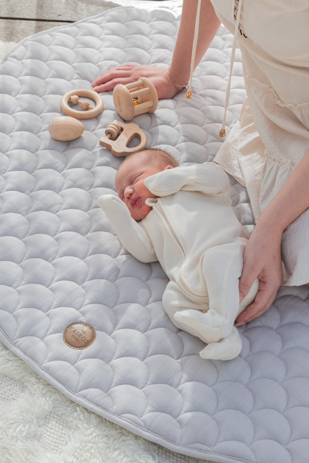 A newborn lying comfortably with toys on The Kairos Child best baby play mat.
