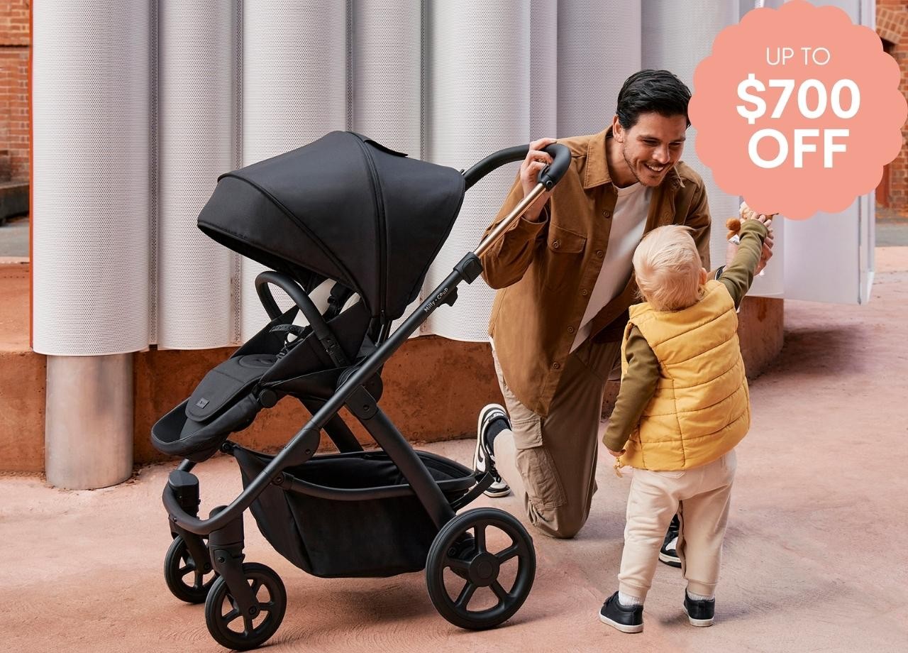 A dad playing with son next to a Milly + Coup pram
