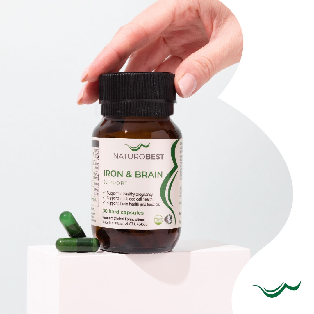 Best iron supplement Australia – close-up of iron pills being selected next to pregnancy health supplement bottles.