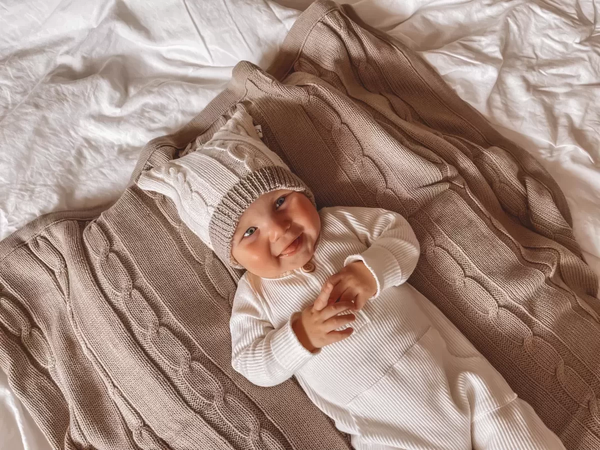 A baby lying on a brown baby blanket
