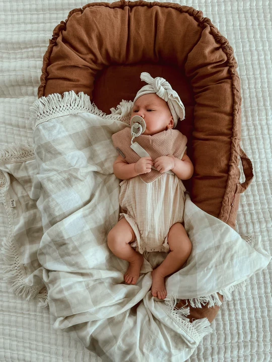 The Audrey & Me baby lounger shown with a baby on it, on top of a throw blanket.