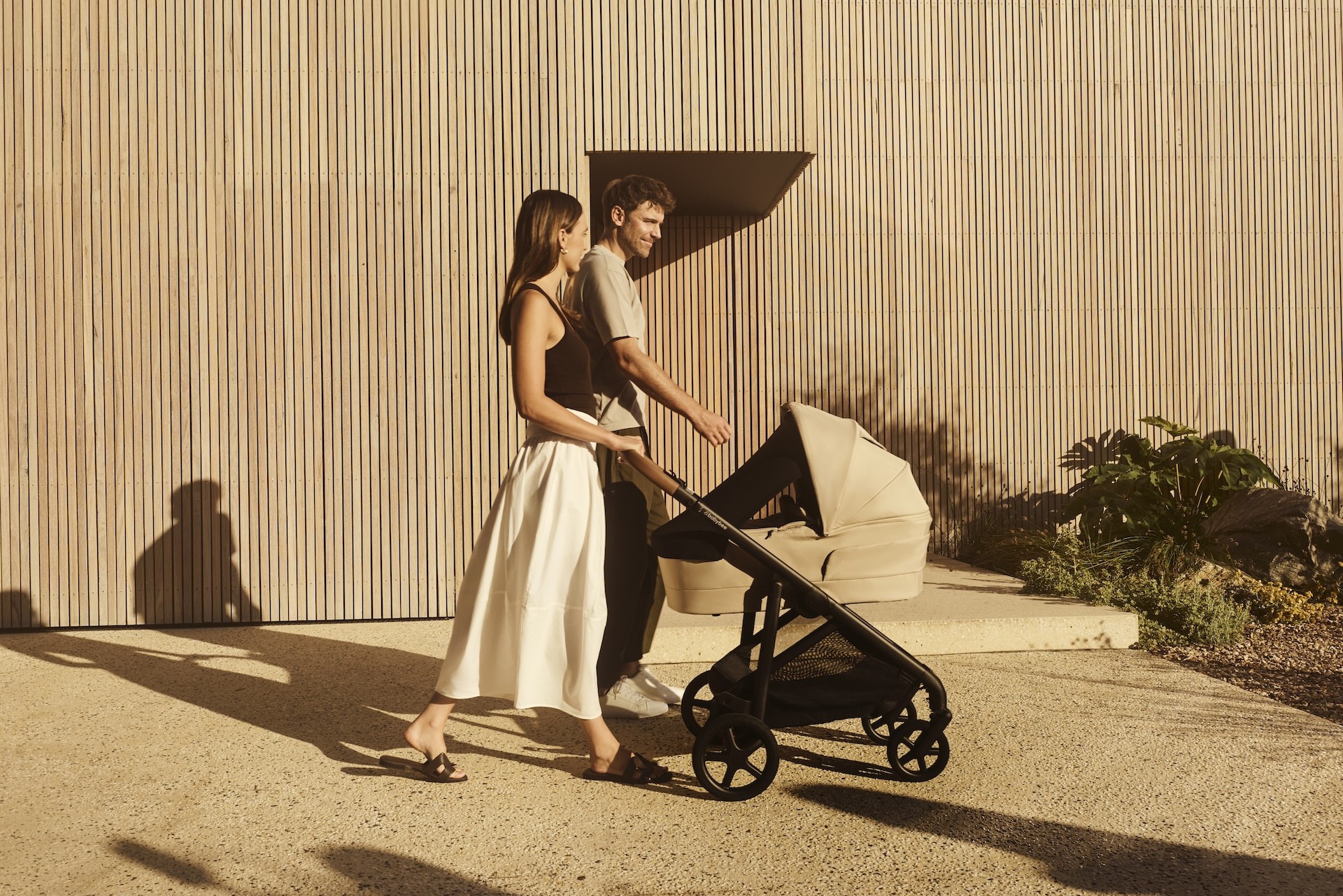 A couple walking with their baby at sunset