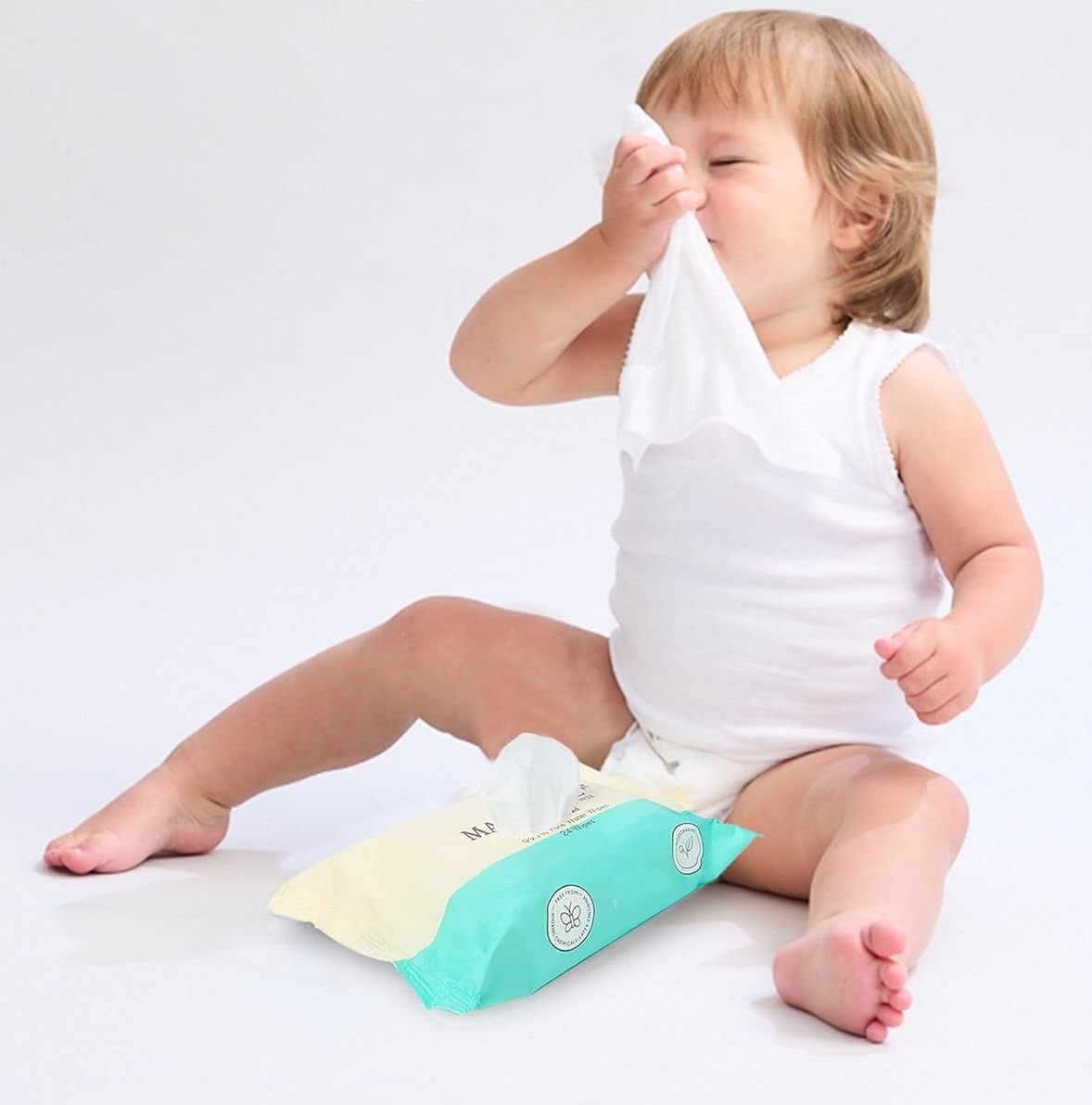 a baby holding the marquise baby wipes up to its face