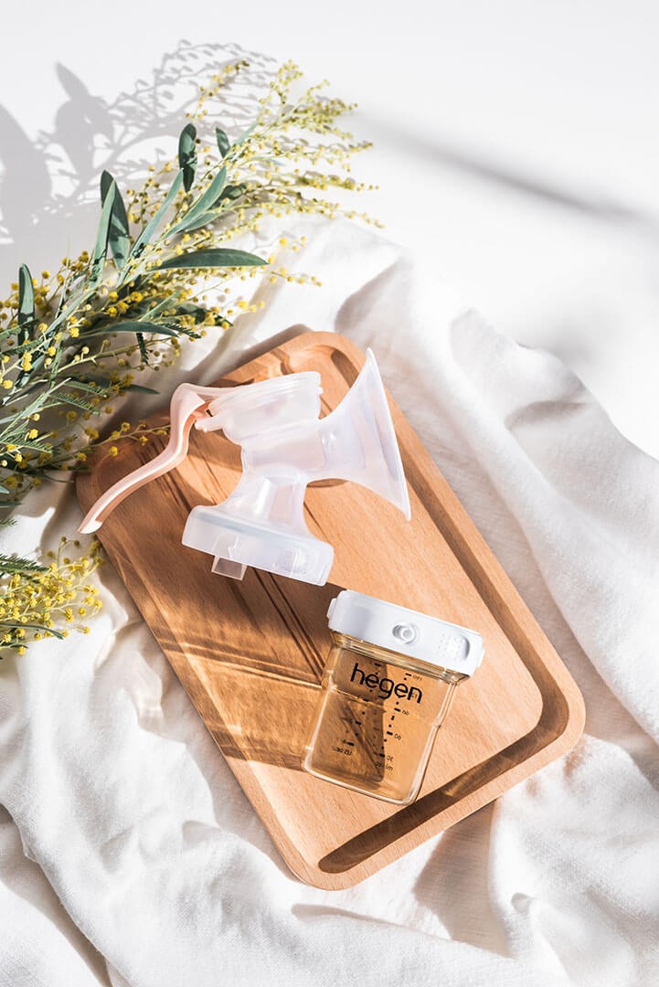 A Hegen Manual Breast Pump on top of a wooden tray
