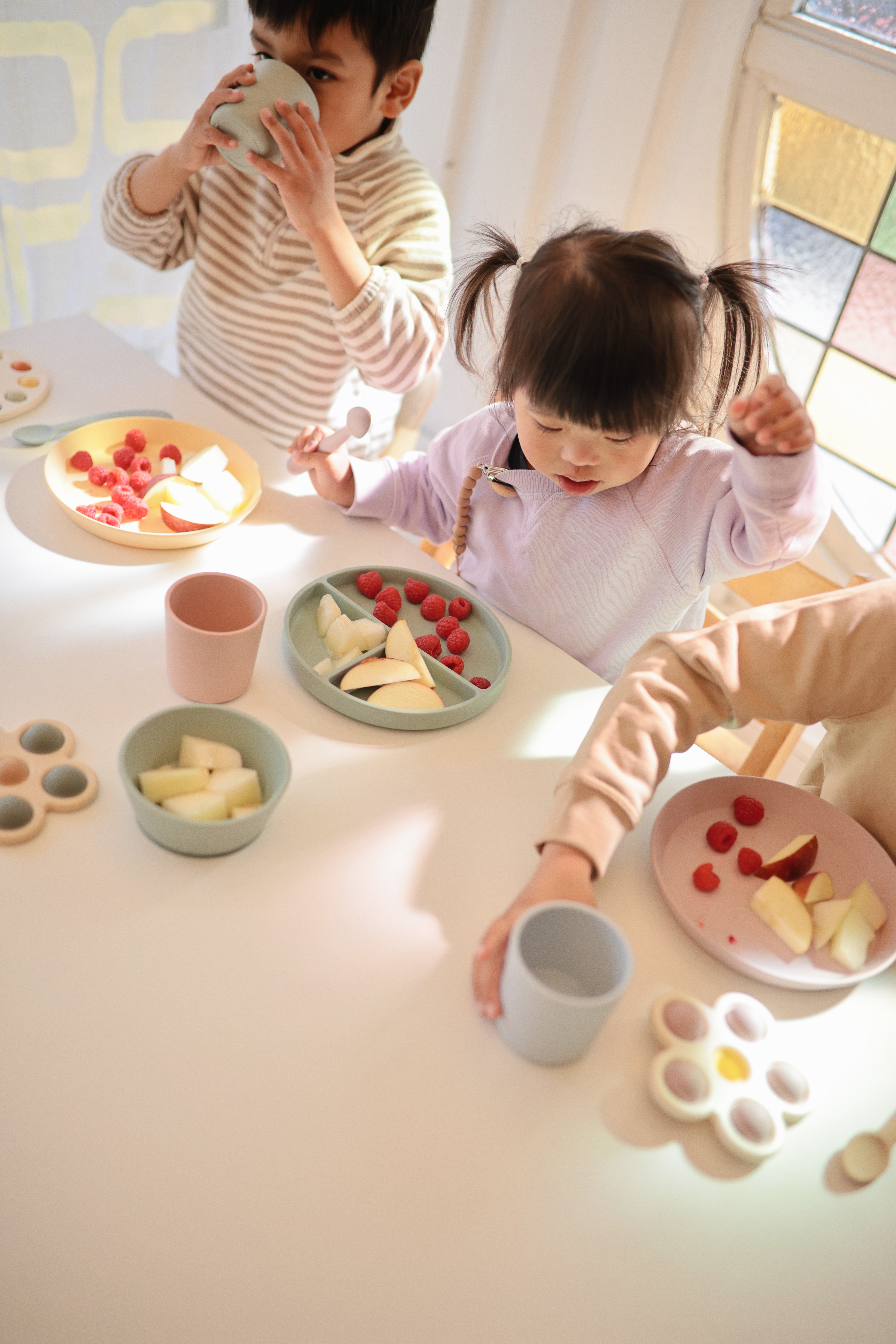 Babies eating from Bella Dinnerware, the Best Feeding Essential for a clean and enjoyable starting solids experience.
