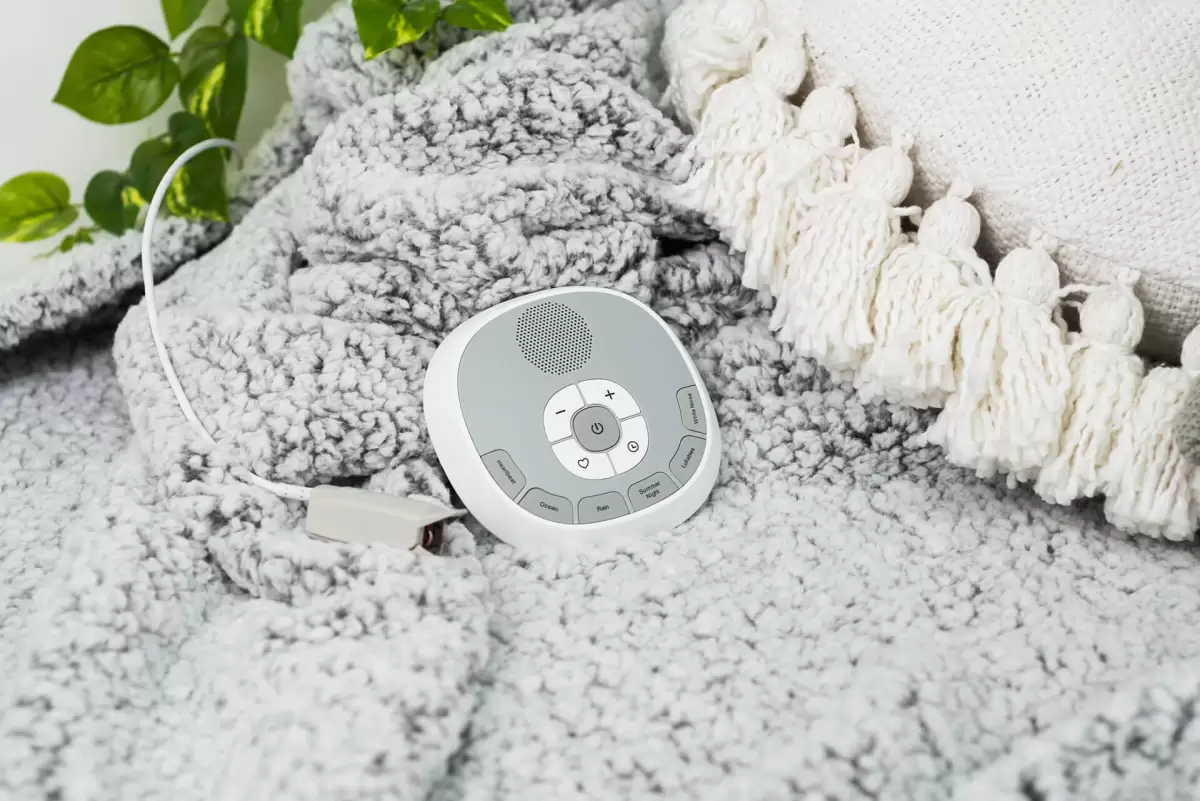 Grey Welcare white noise machine placed on a soft grey knitted rug – minimalist and soothing nursery essential