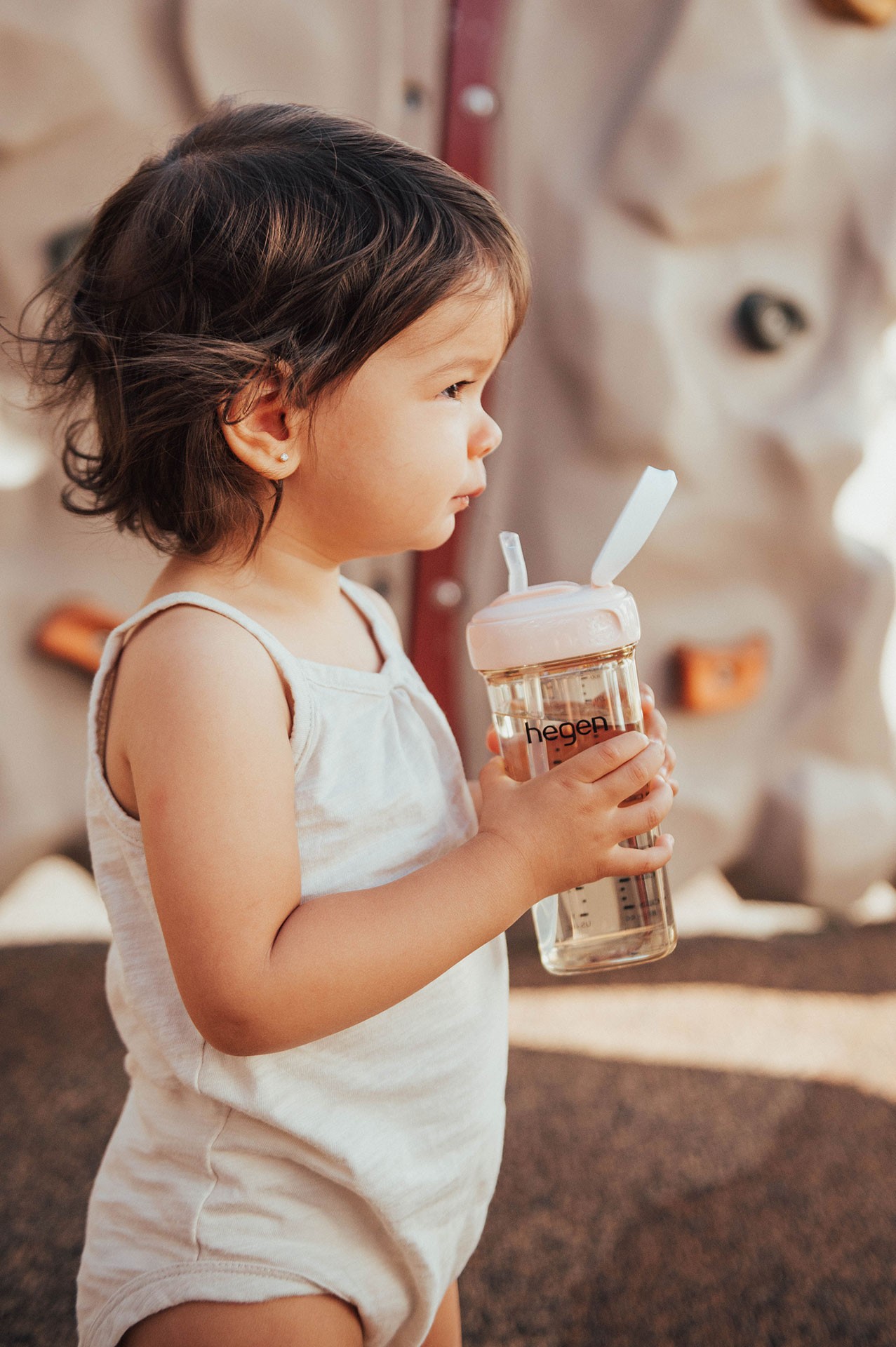 A girl on the playground taking a break and holding the best water bottle for kids filled with water for quick refreshments
