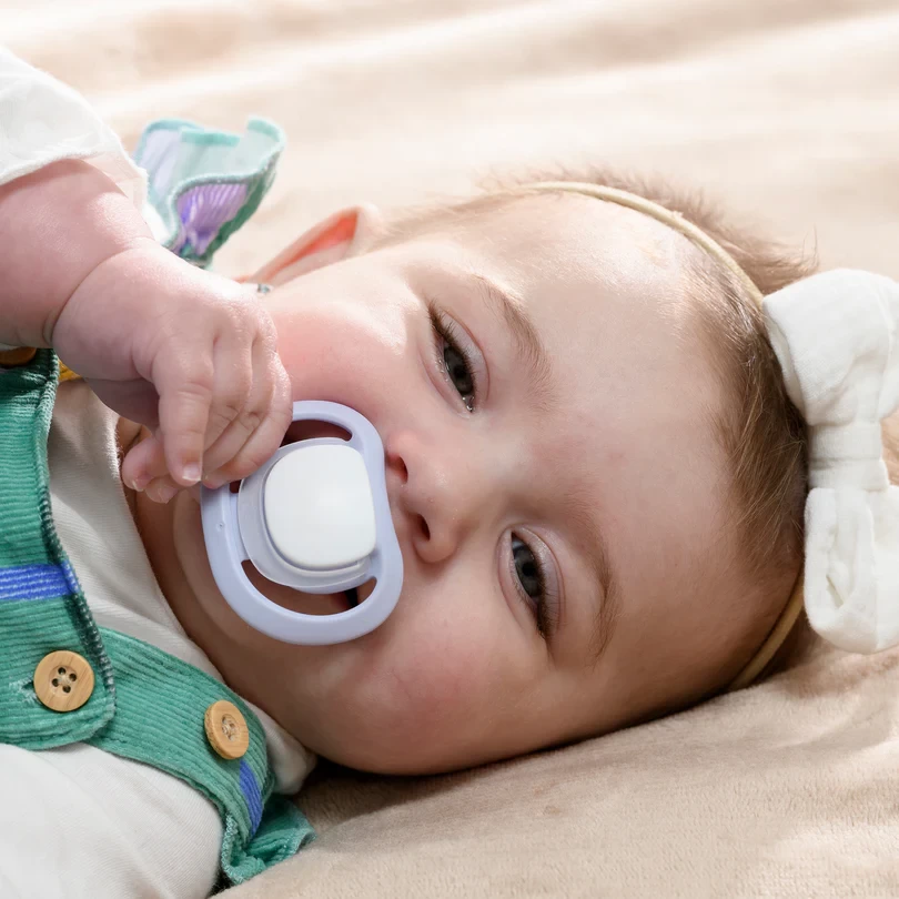 A baby looking at the camera using the Pigeon Skin Friendly dummy in australia
