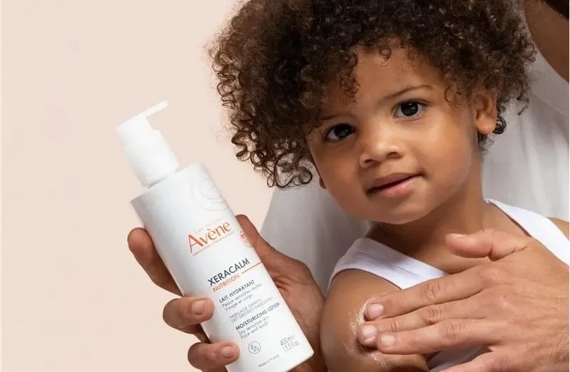 A little boy being held by his dad who is also holding Avene Xeracalm Lotion