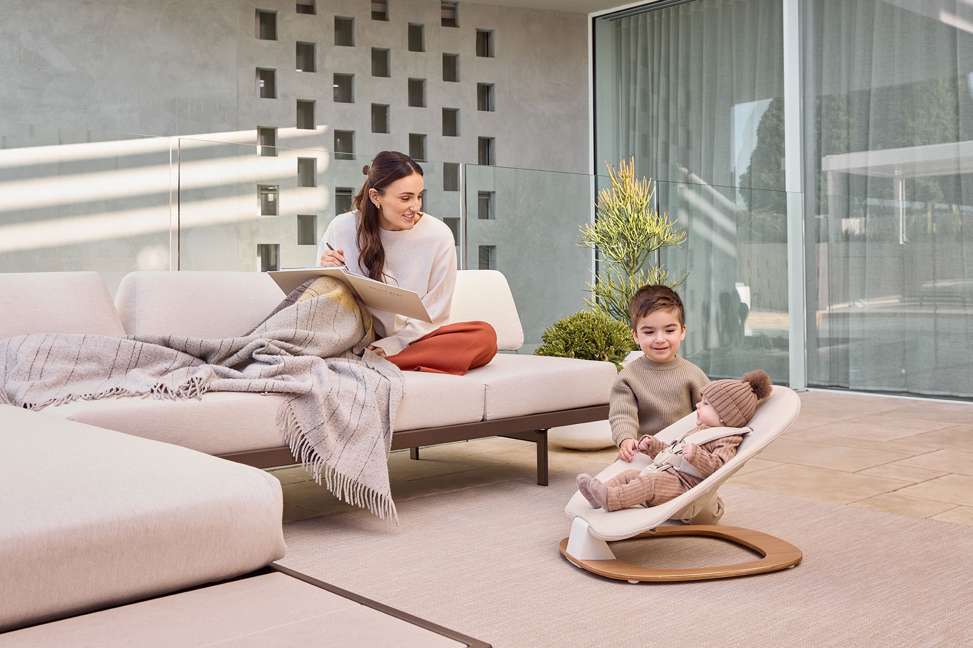Parent admiring toddler and baby bonding, with the newborn baby bouncer as an essential family item.