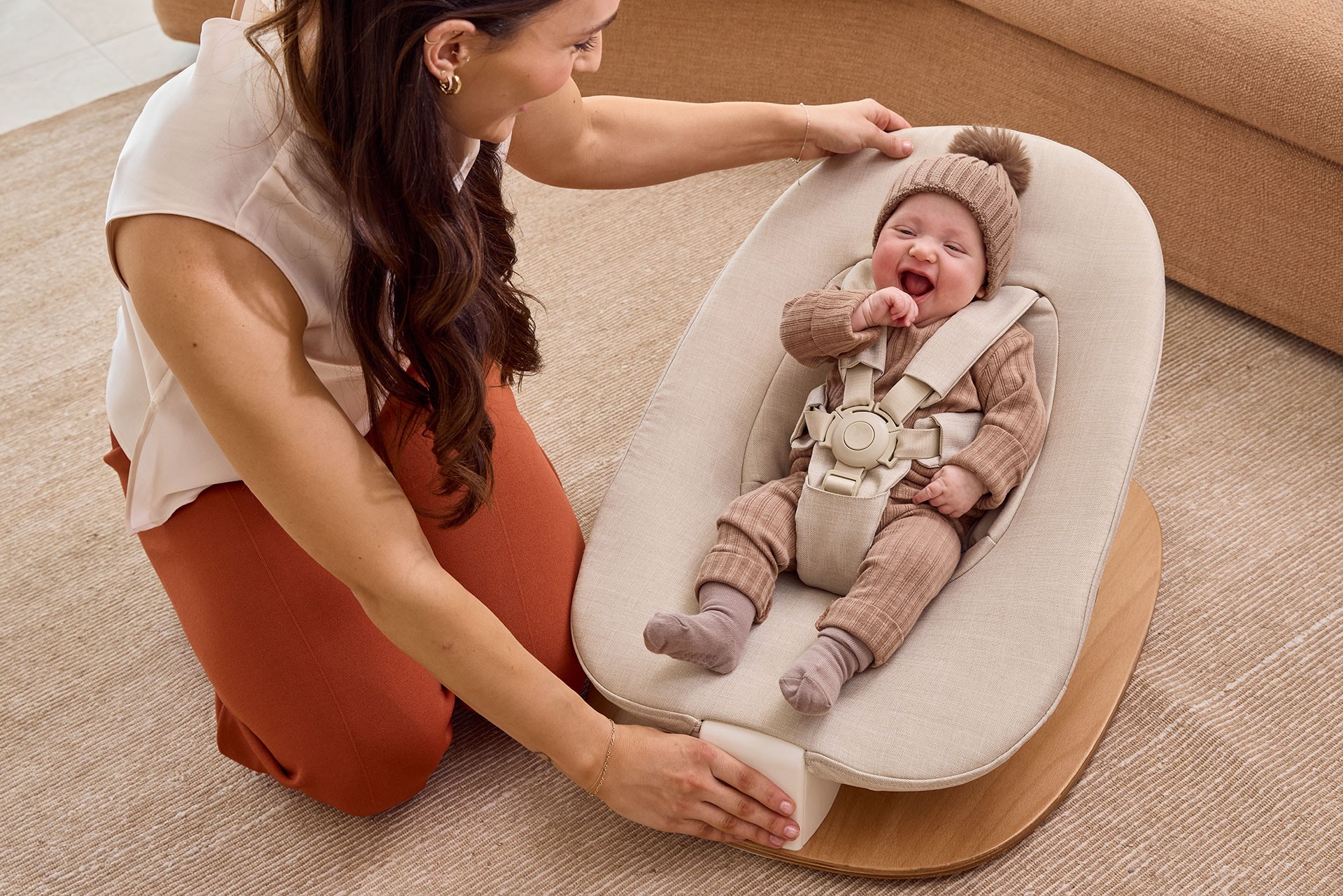 Newborn baby resting safely in a Redsbaby compact newborn baby bouncer as mum engages playfully.
