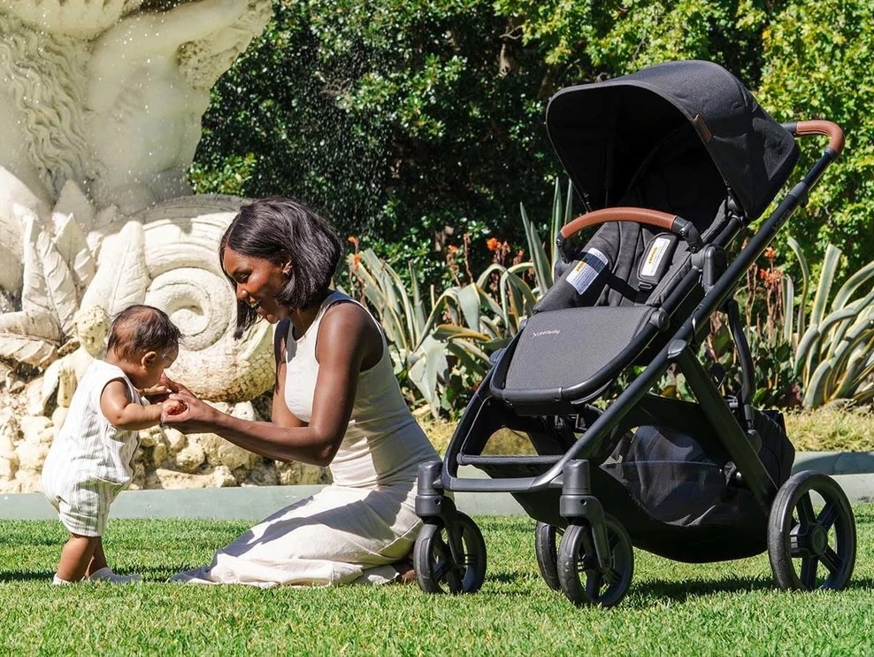 A mum playing with her baby next to the Uppababy Vista V3 double pram