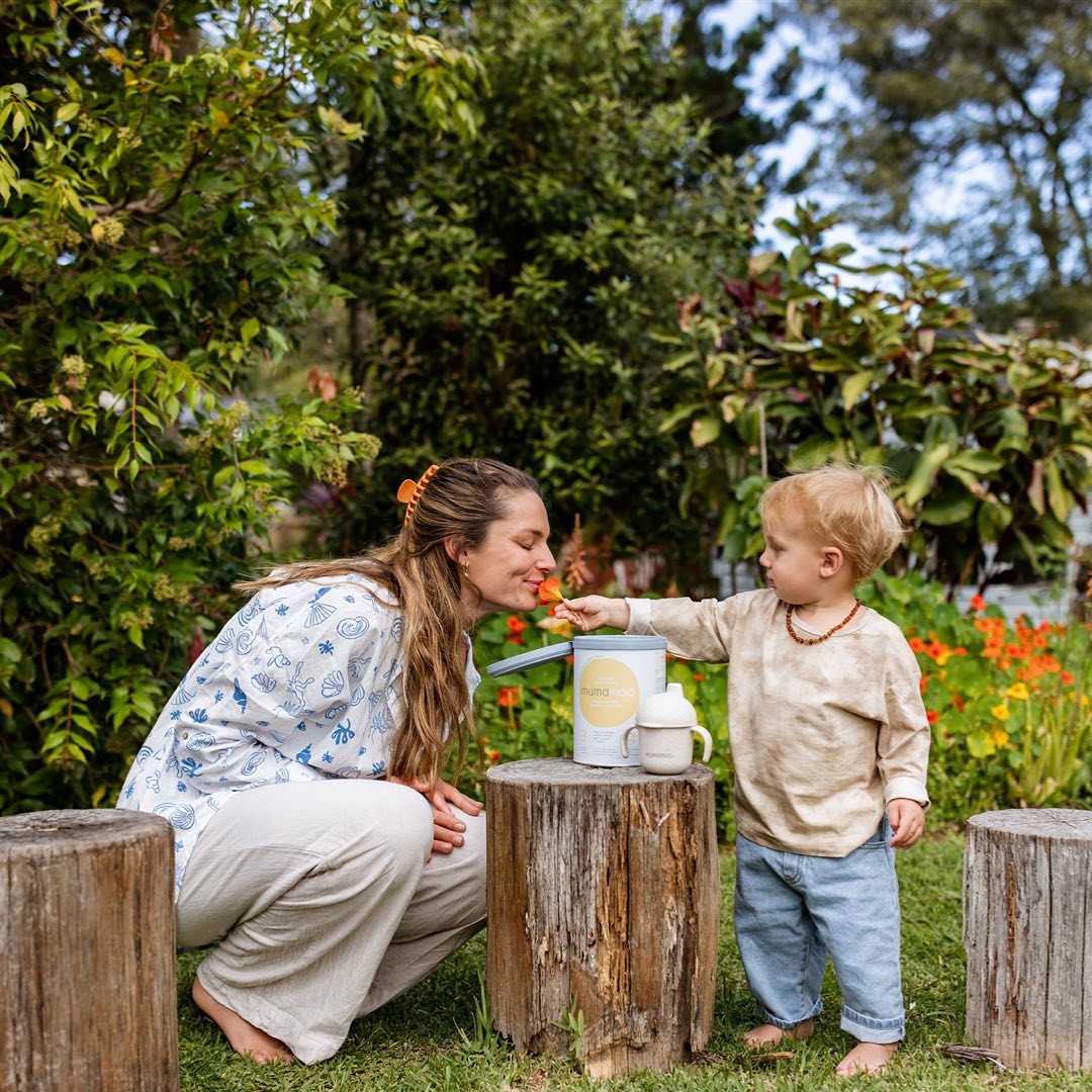 Mother and toddler in the garden with Mumamoo Formula Stage 3 Premium Toddler Milk Drink tin on a wooden stump
