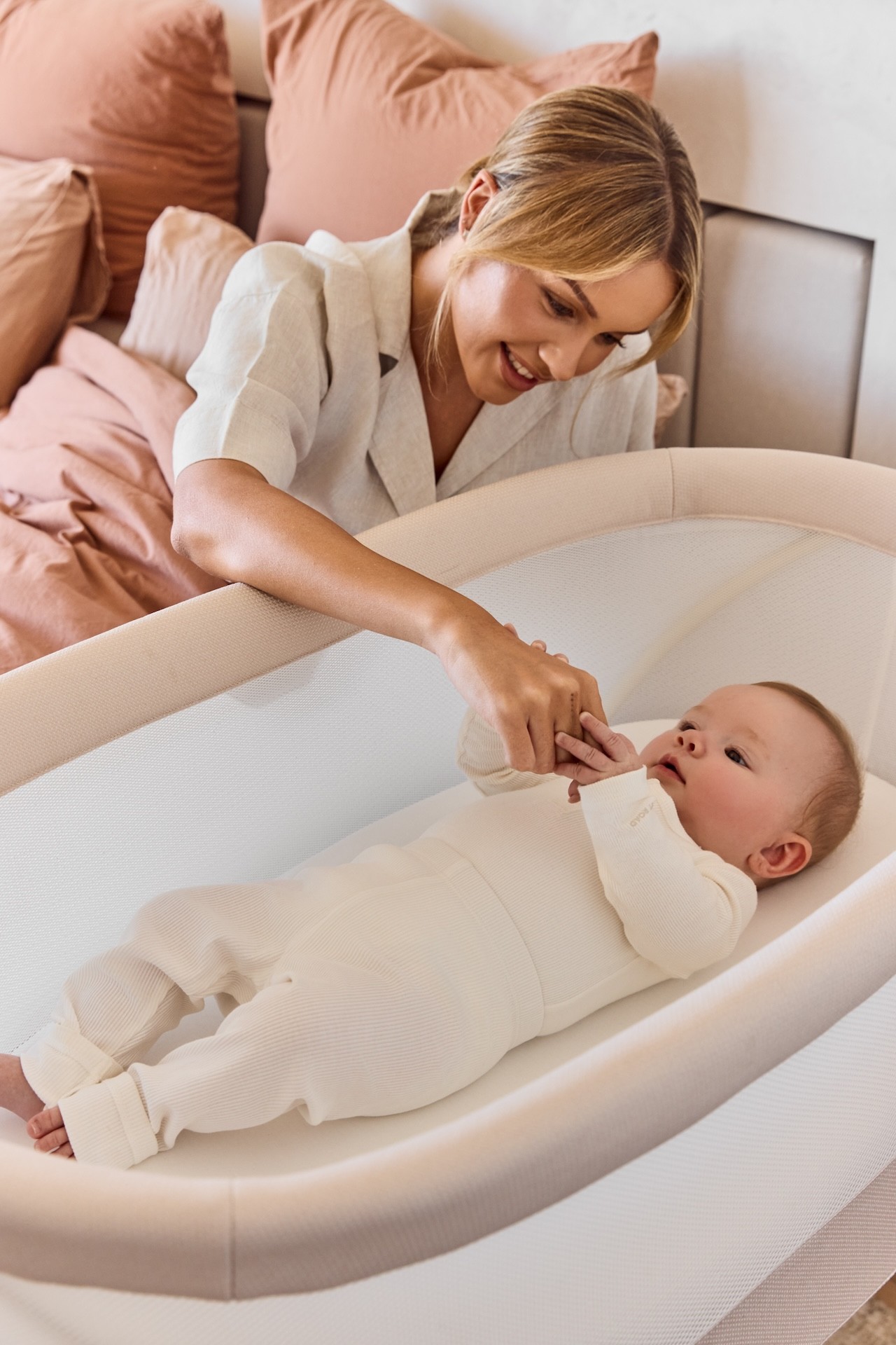 An Australian mum tending to her baby in the KIPP bassinet as its beside her bed