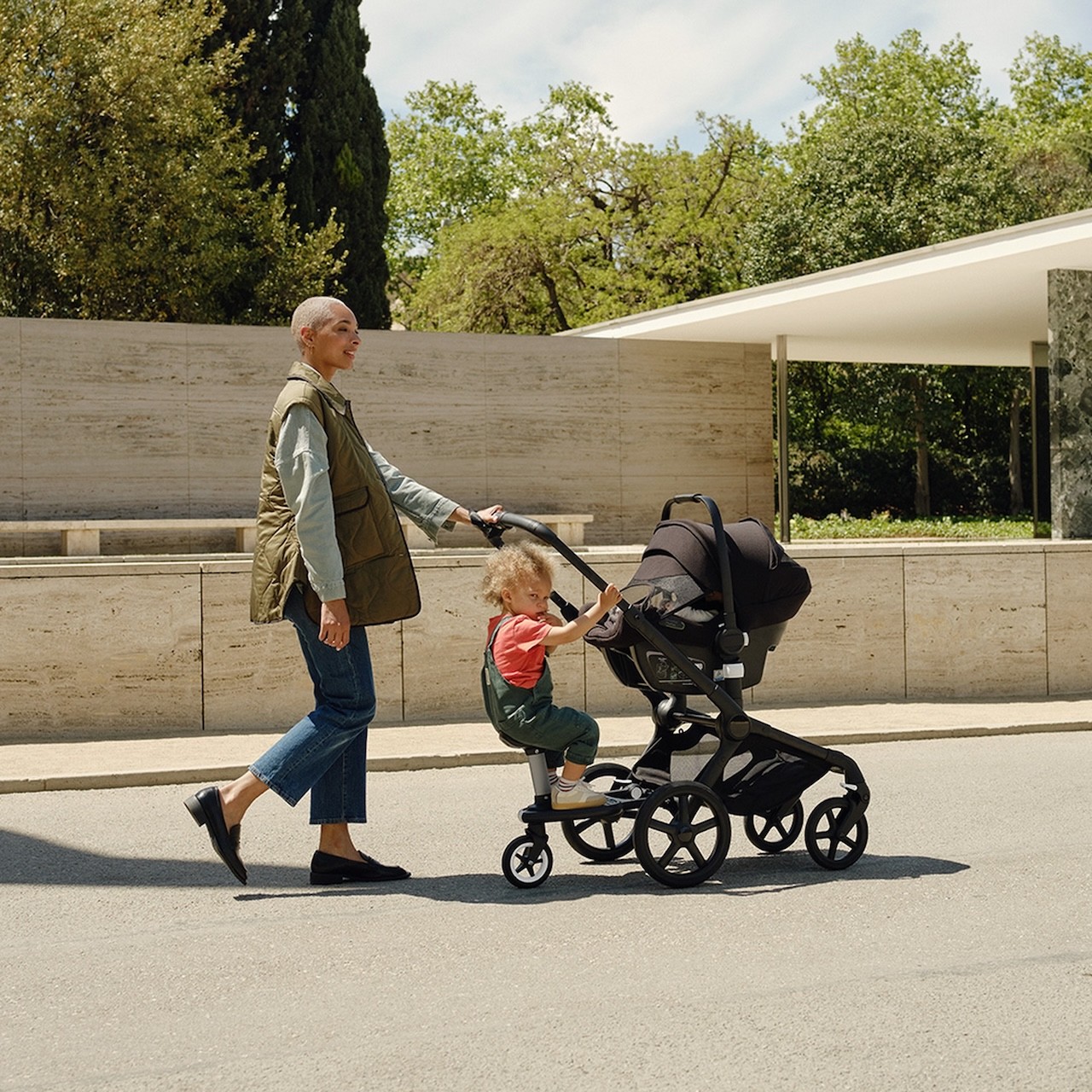 An Australian mum pushing her Bugaboo Fox 5 pram with a toddler on the riding board attachment.