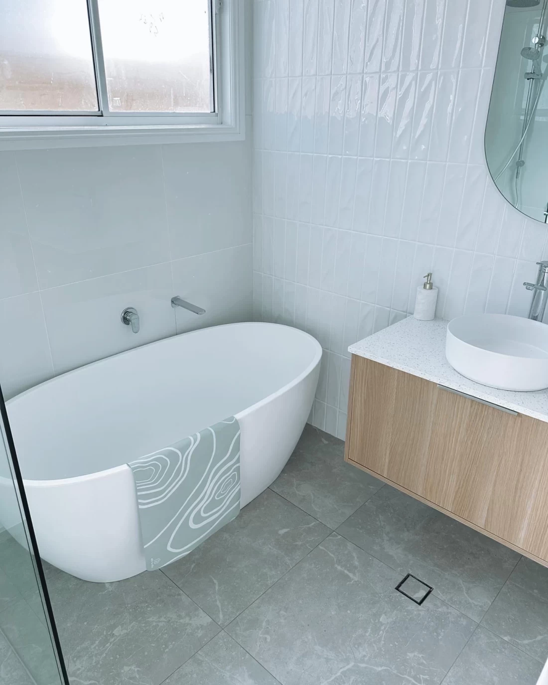 Best bath mat hanging neatly over the bathtub edge in a modern bathroom.
